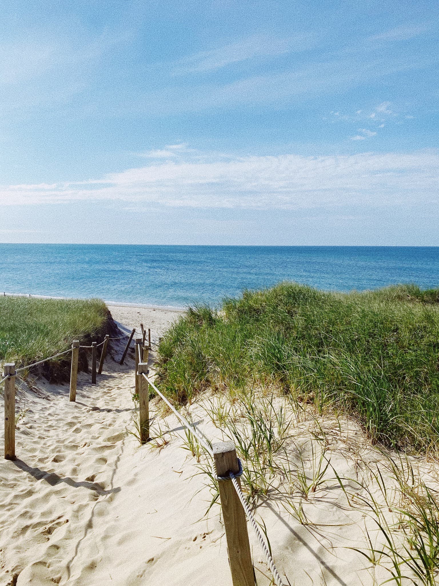 View of a sandy pathway leading down to the beach and a calm sea