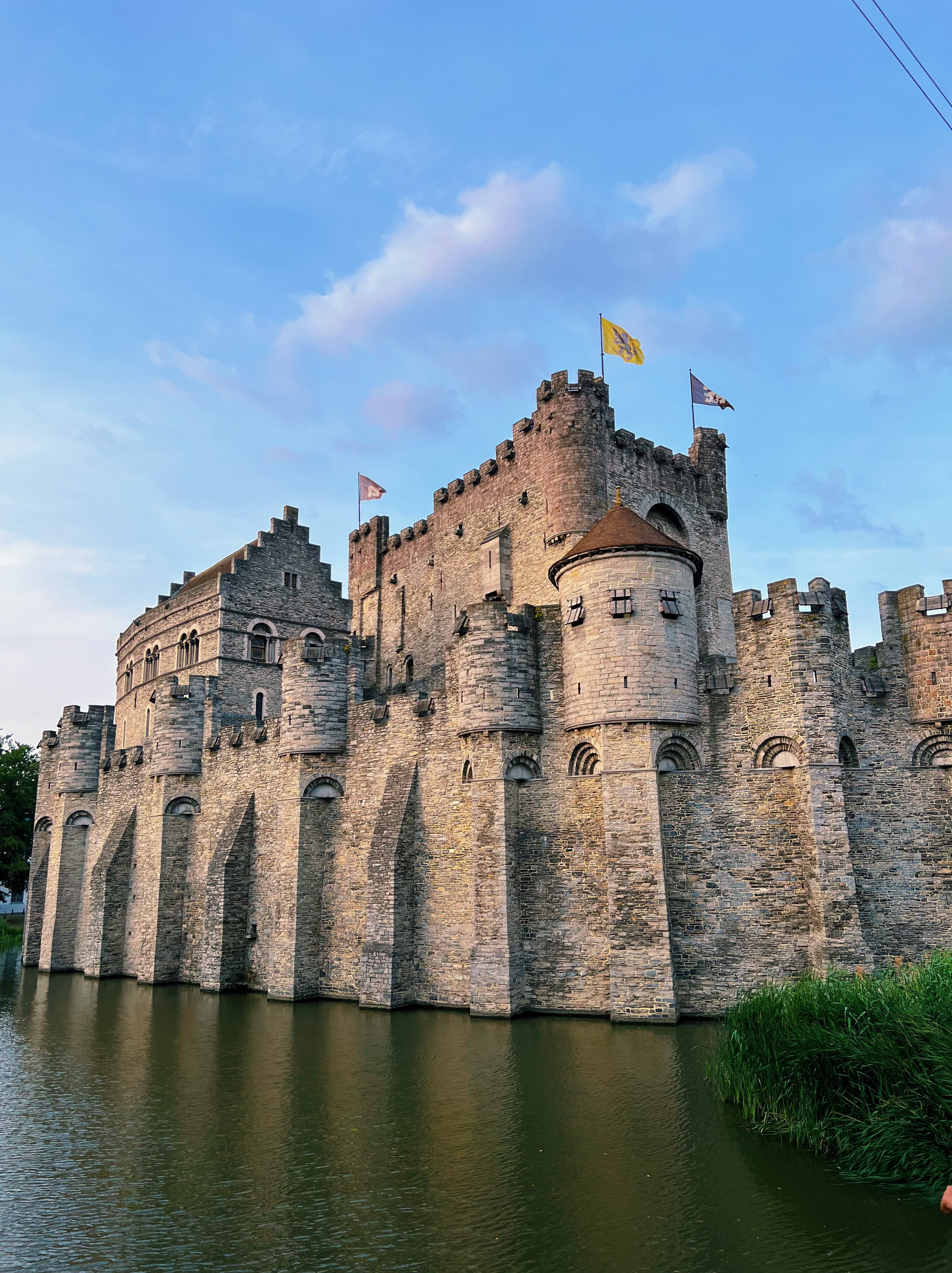 View of an old castle fortress on the water with yellow flags flying from each tower