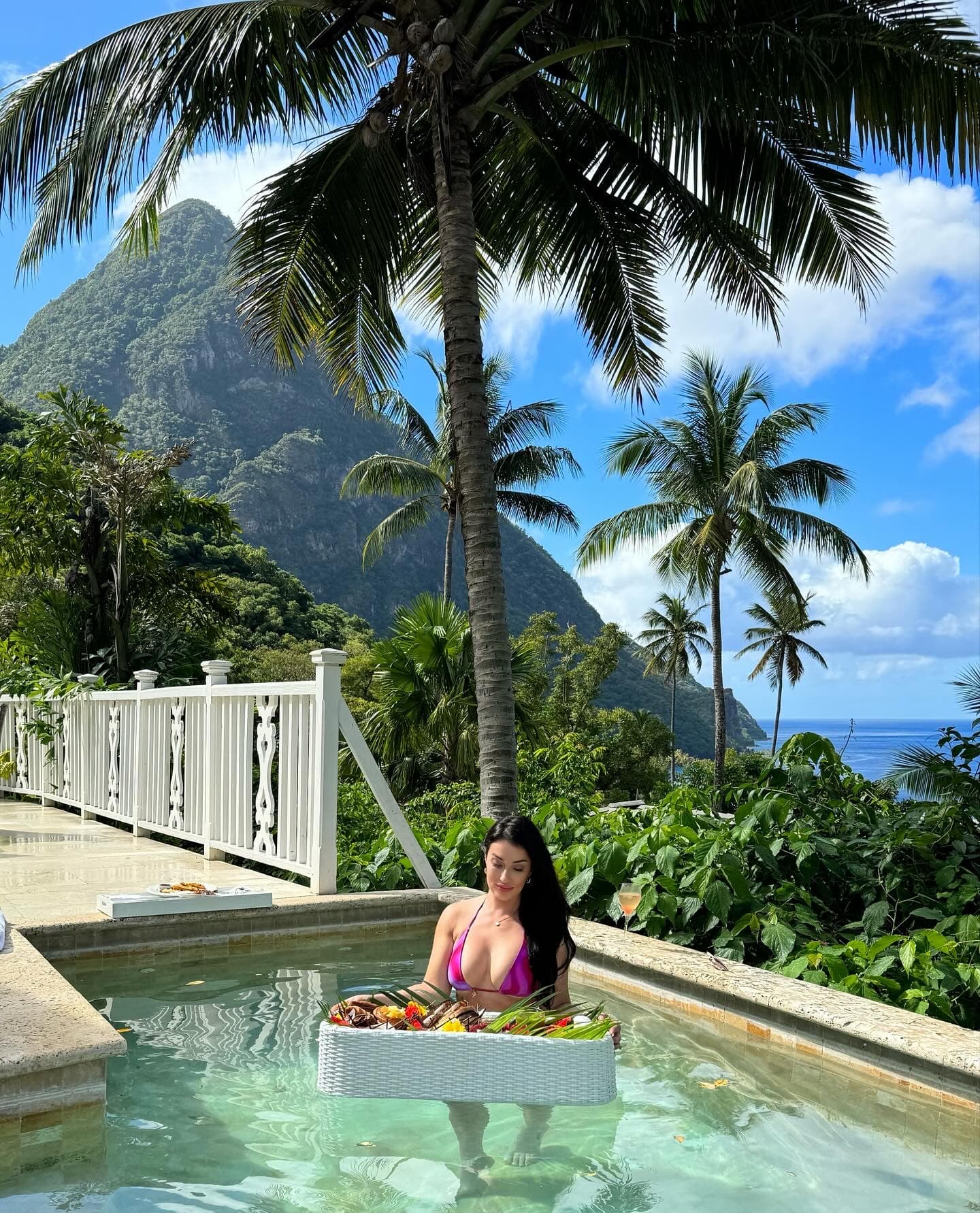 Advisor in a private plunge pool with a floating tray of food and gorgeous tropical views behind her