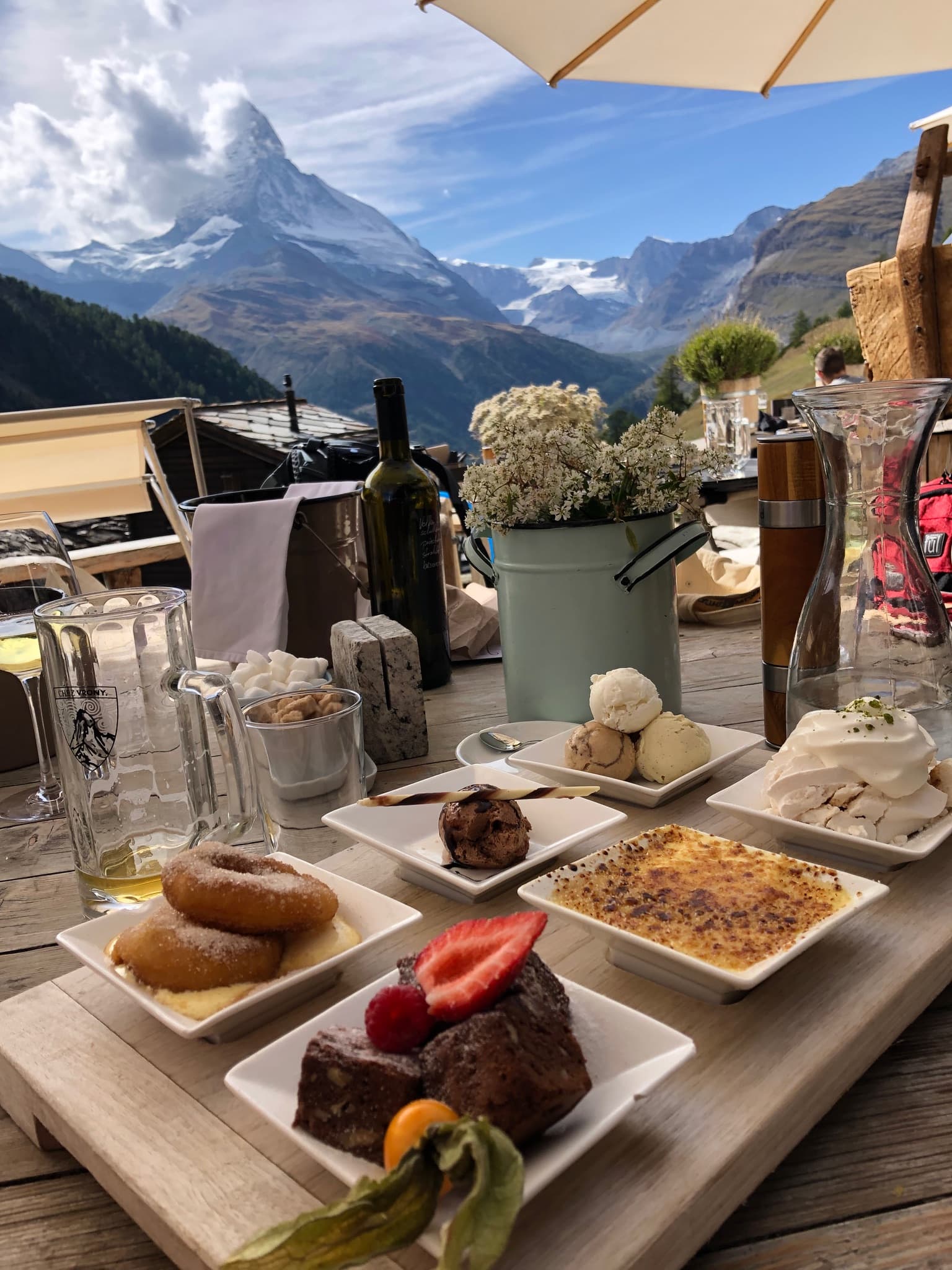 View of a table with large plates of various food and a beautiful mountain view