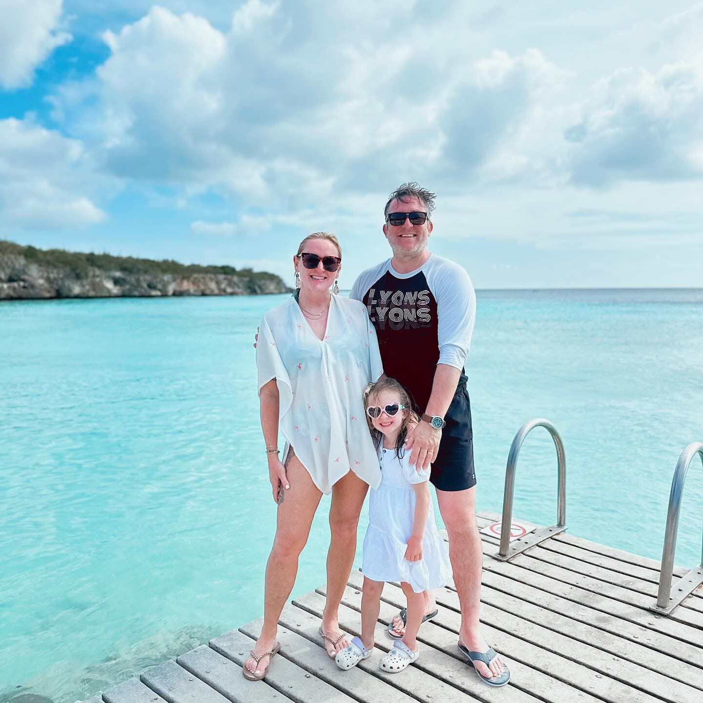 Advisor and family on a wooden dock in Curaçao with crystal clear water behind them