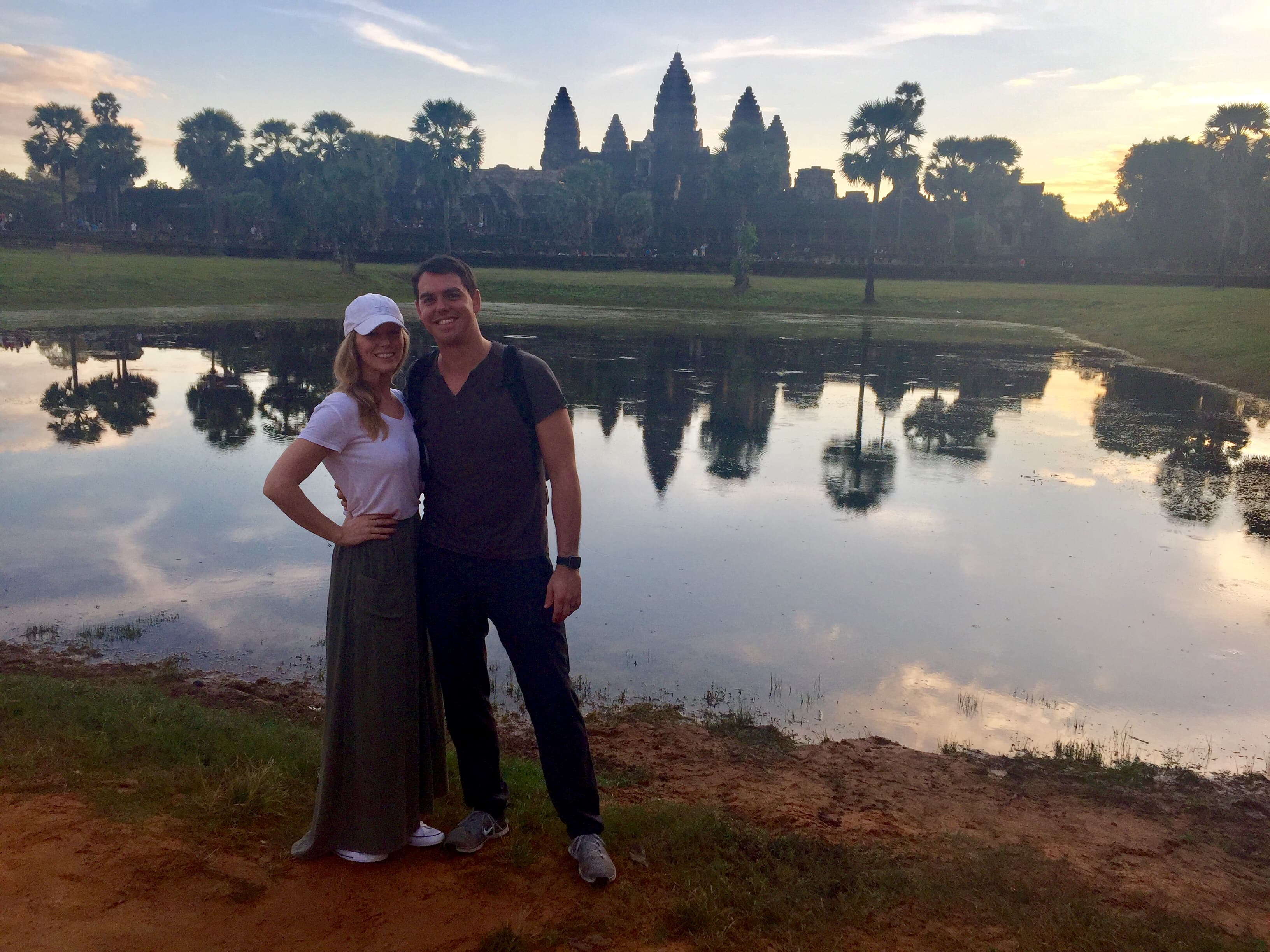 Advisor and partner posing side by side in front of a small pond at sundown