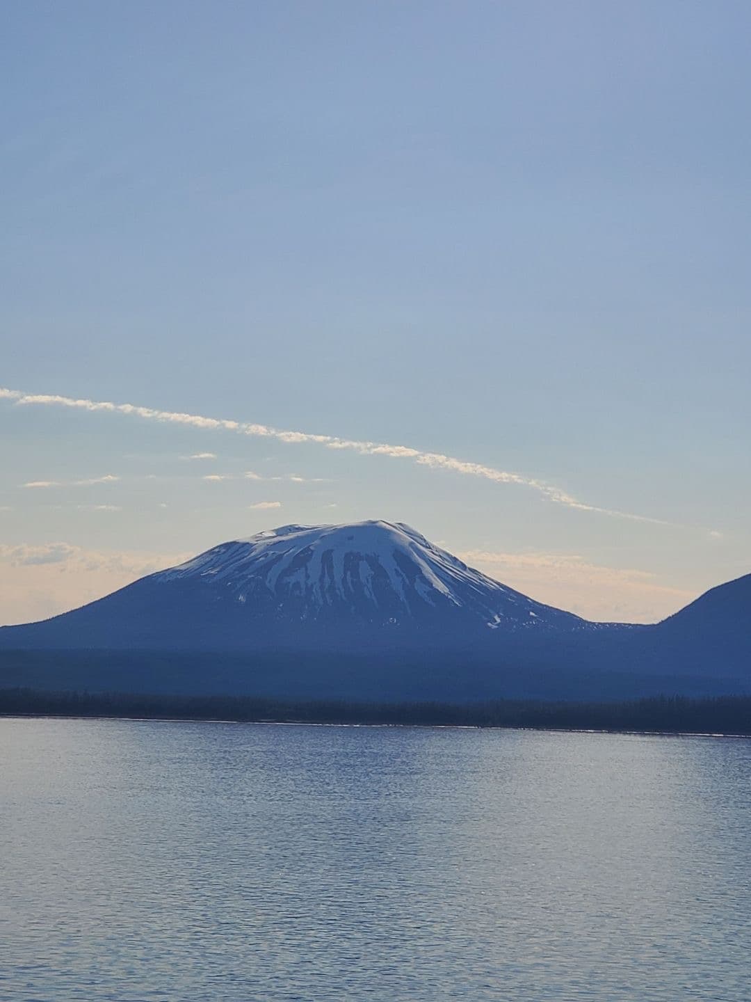 View of a large volcano seen from across the water under clear skies