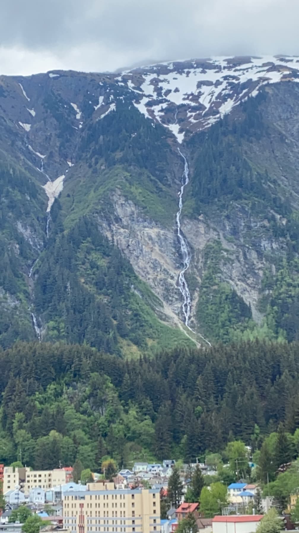 View of a mountain range with snow at the peaks on a cloudy day