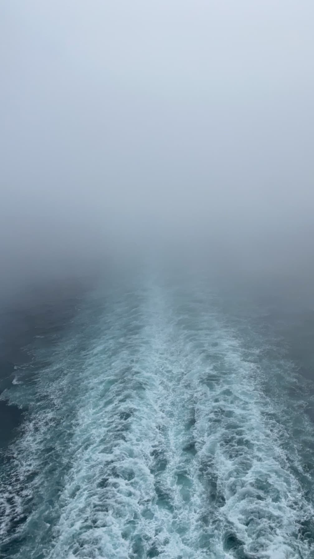 View of the wake of a boat in the sea on a foggy day
