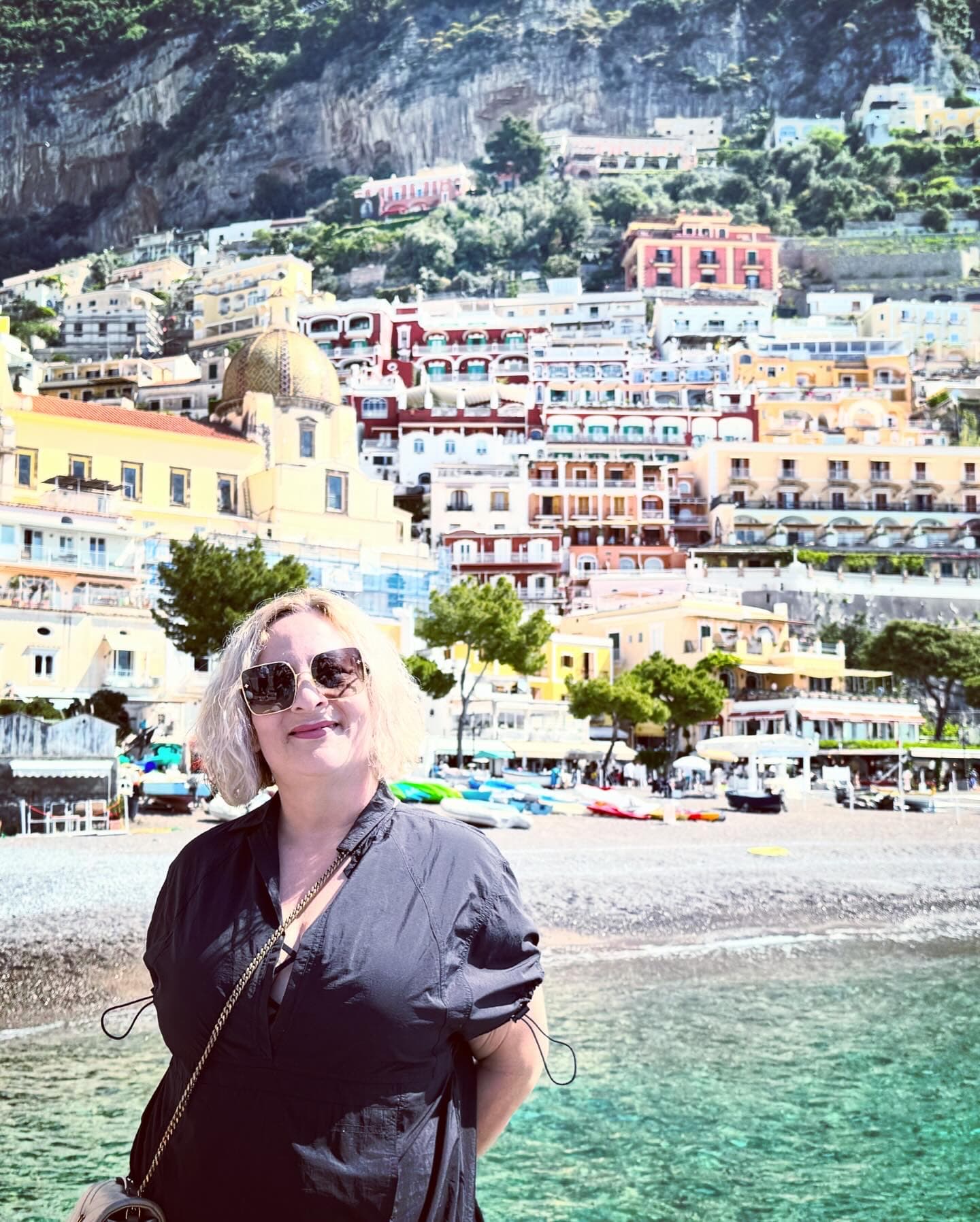 Advisor smiling on a sunny day with a colorful coastal town on the hill in the background