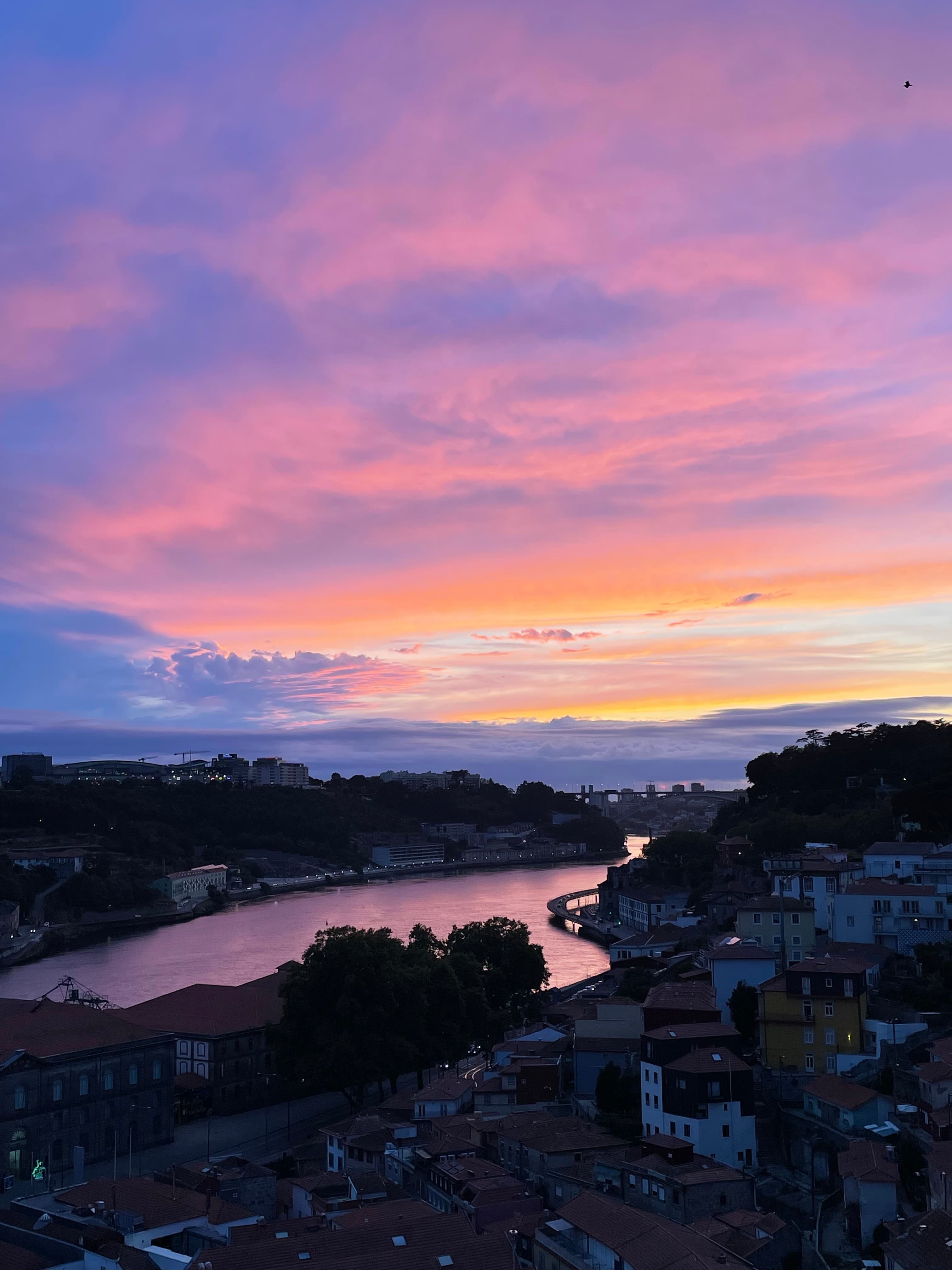 Beautiful pink and purple clouds at sunset over a river and nearby town