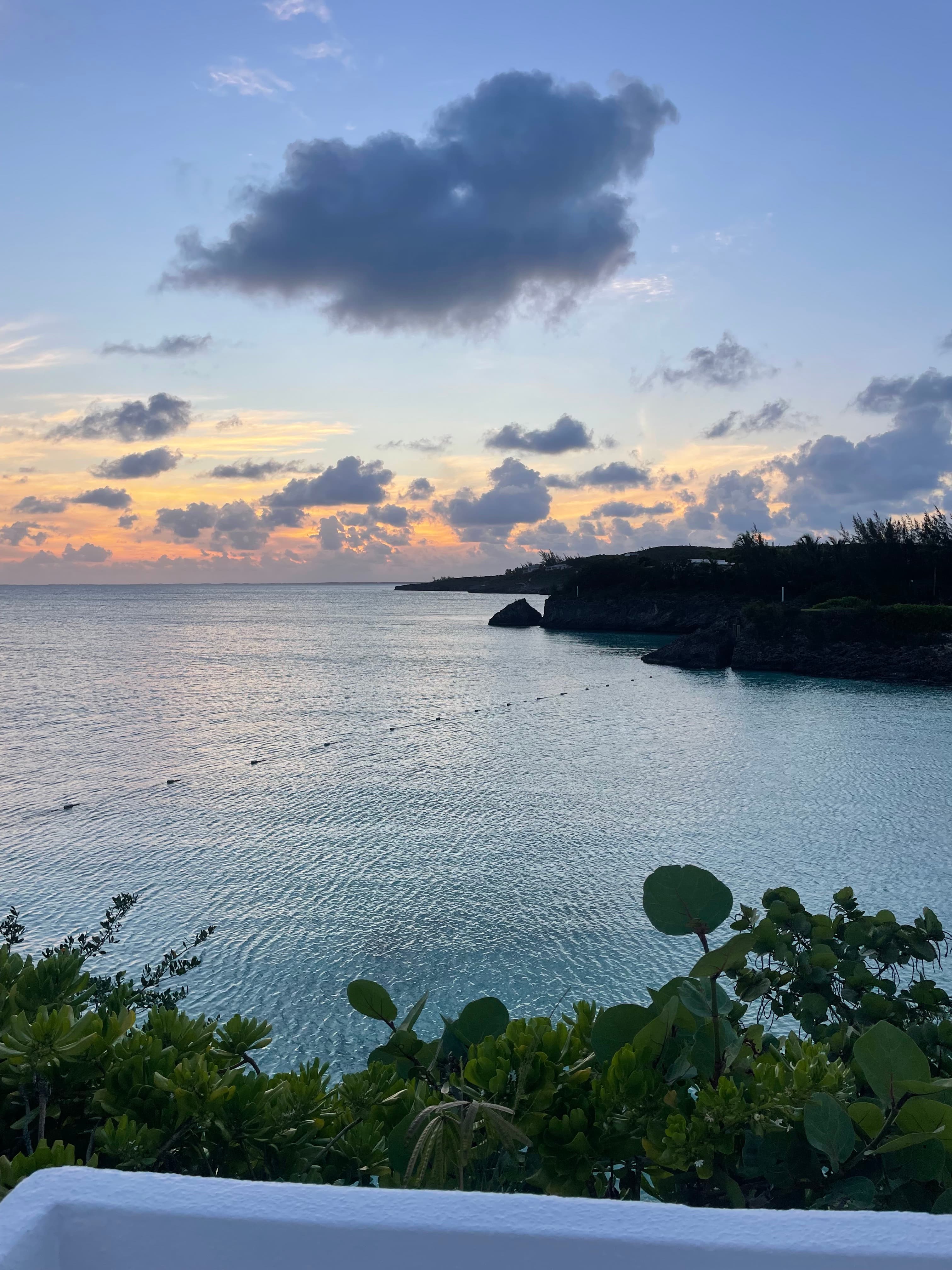 View of a sunset with small clouds over a calm bay