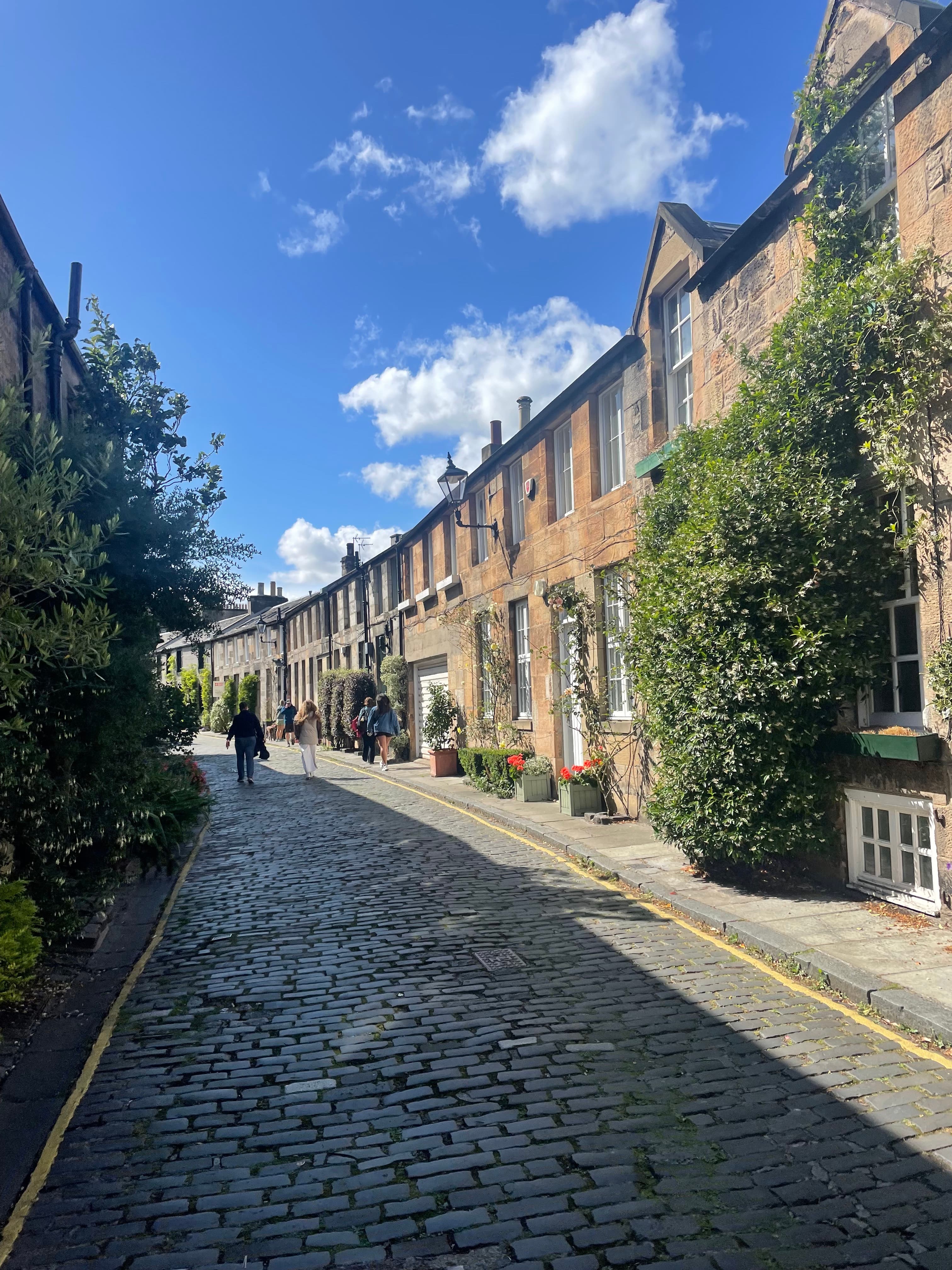 View of a sunny cobblestone street with small brick buildings along one side