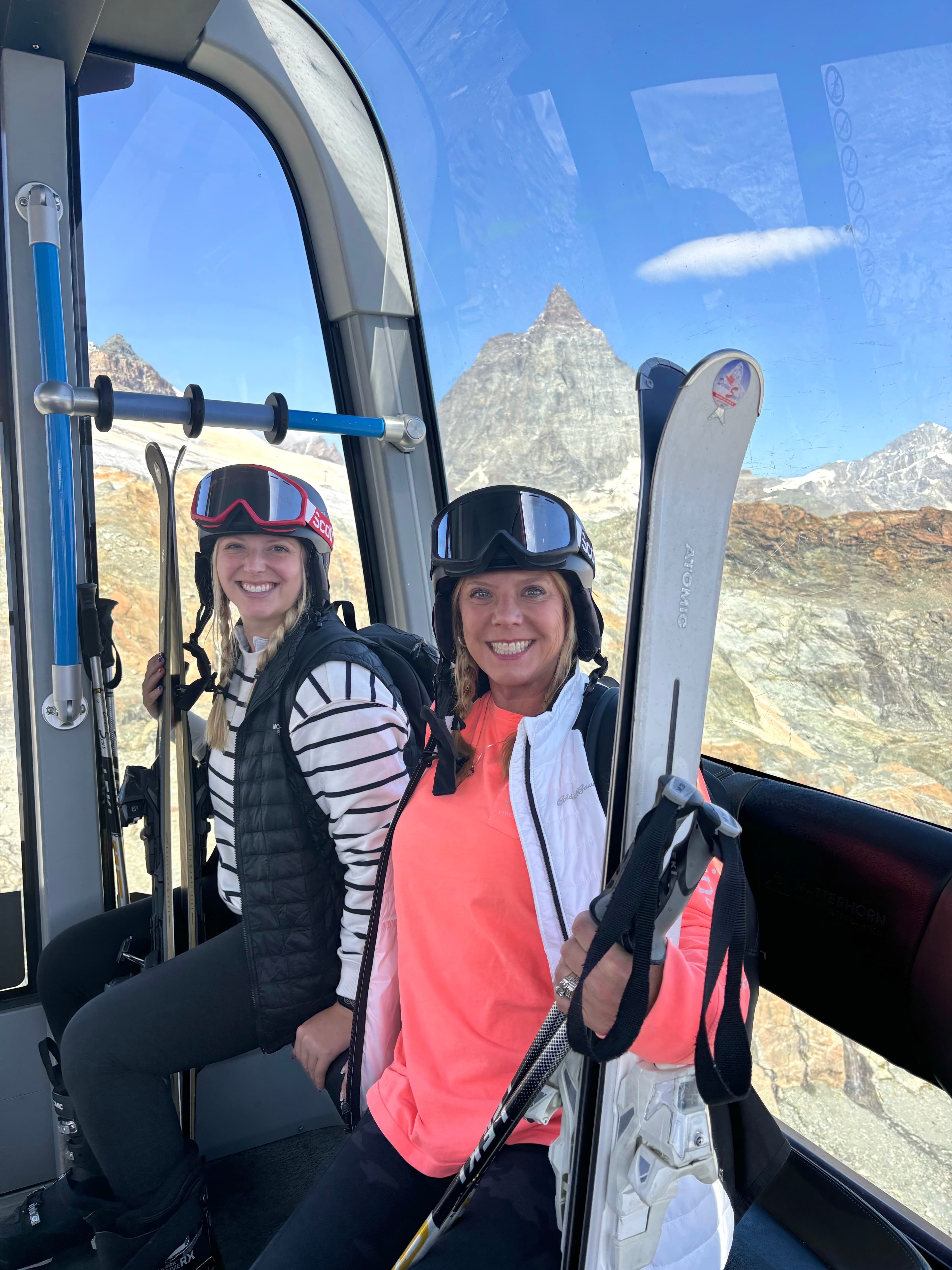 Advisor and friend with ski goggles on their head in a ski lift on a sunny day
