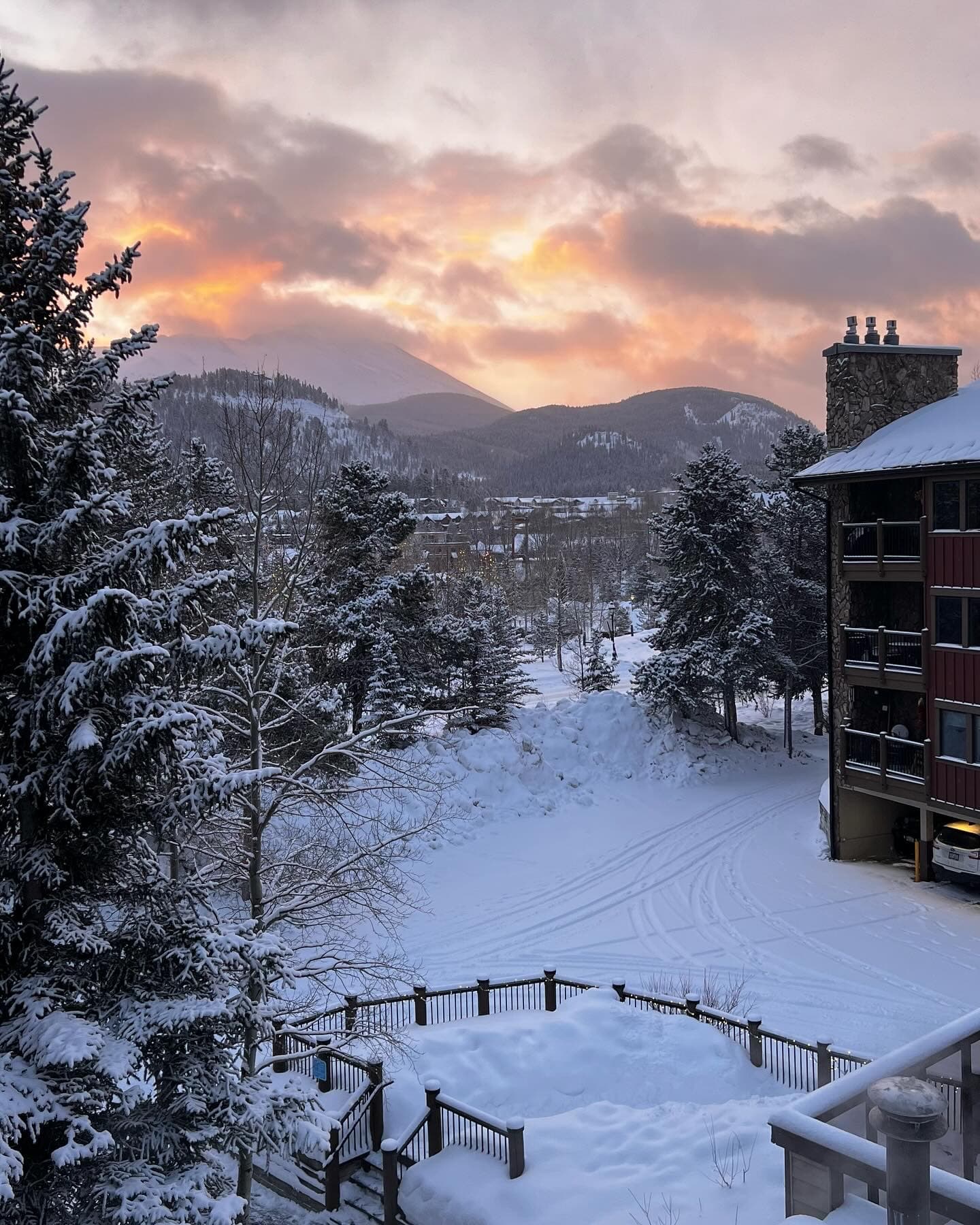 Beautiful view of snowy mountains and a pale orange sunset behind the clouds
