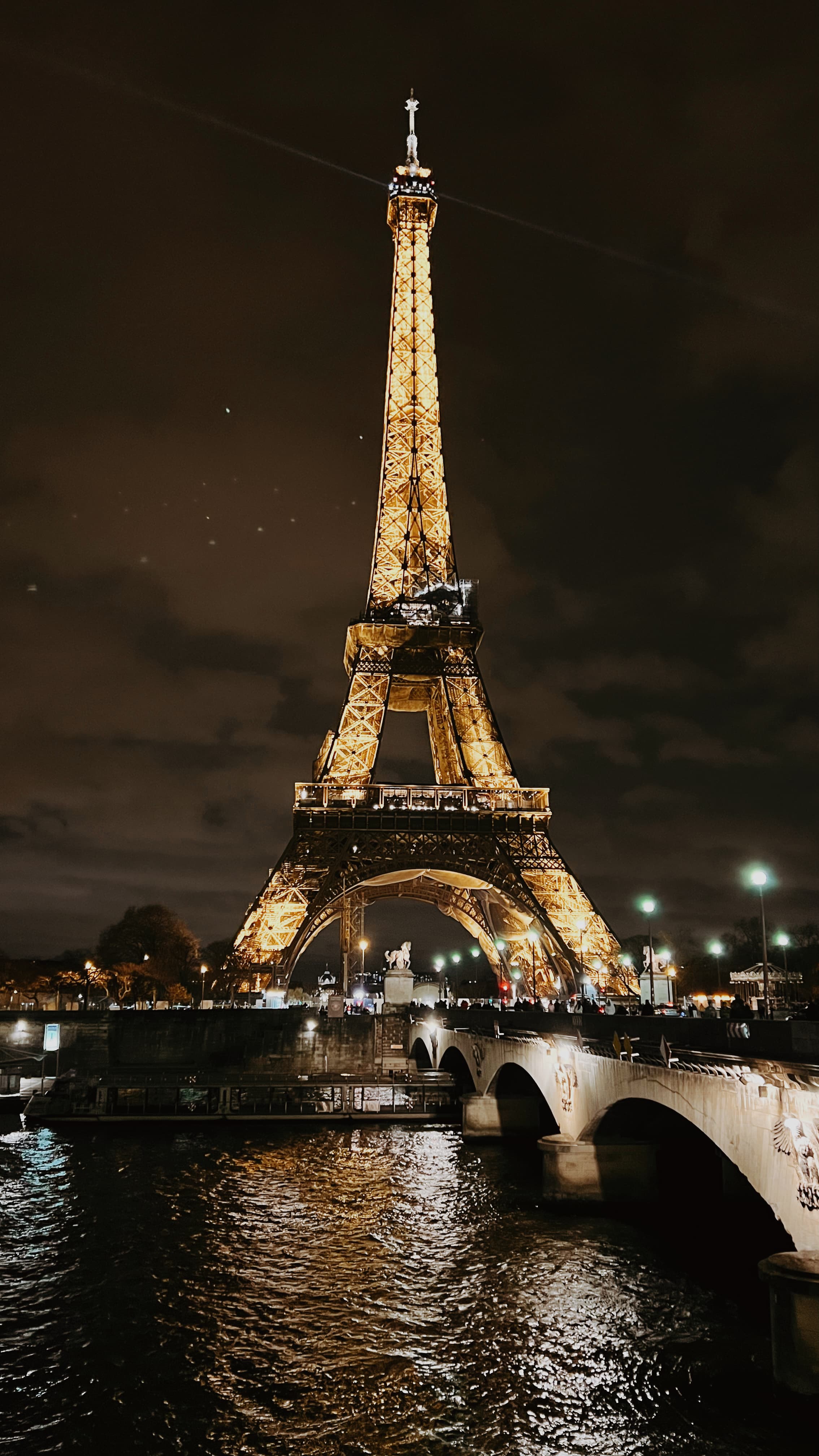 The Eiffel Tower lit up at night seen from across the Seine