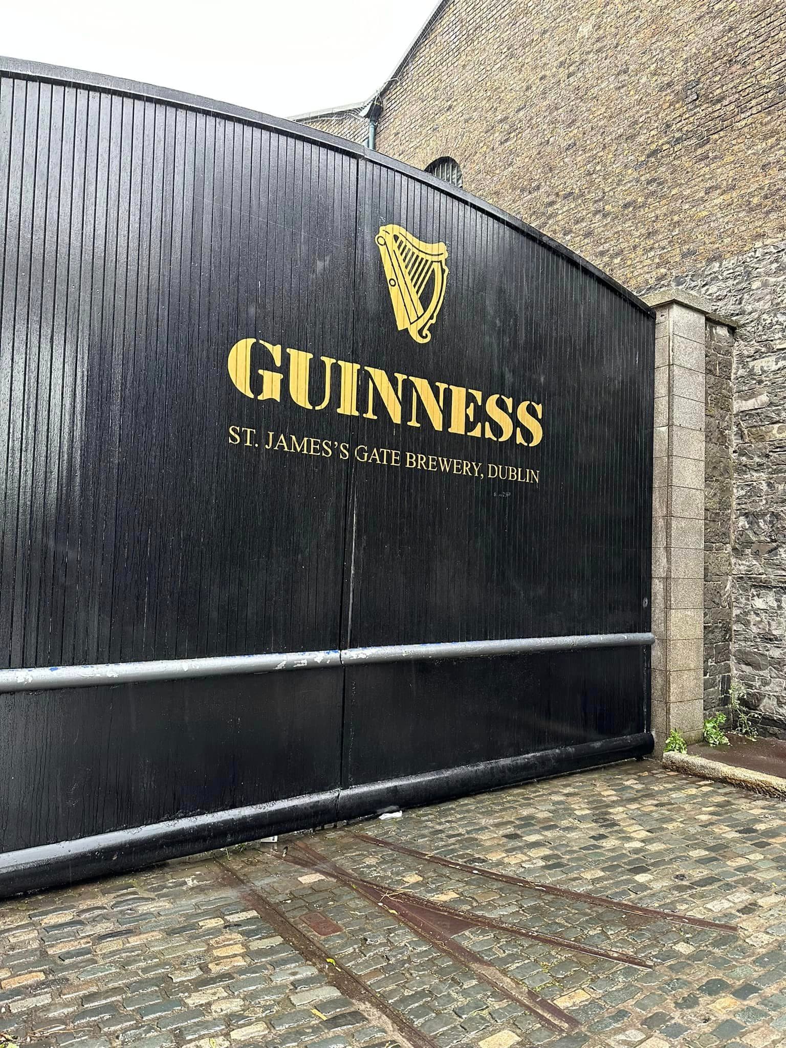 A black fence gate with "GUINNESS" written on it in gold lettering