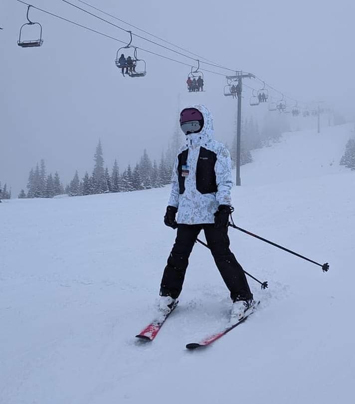 Advisor on skis going down the mountain with the chair lift in behind her