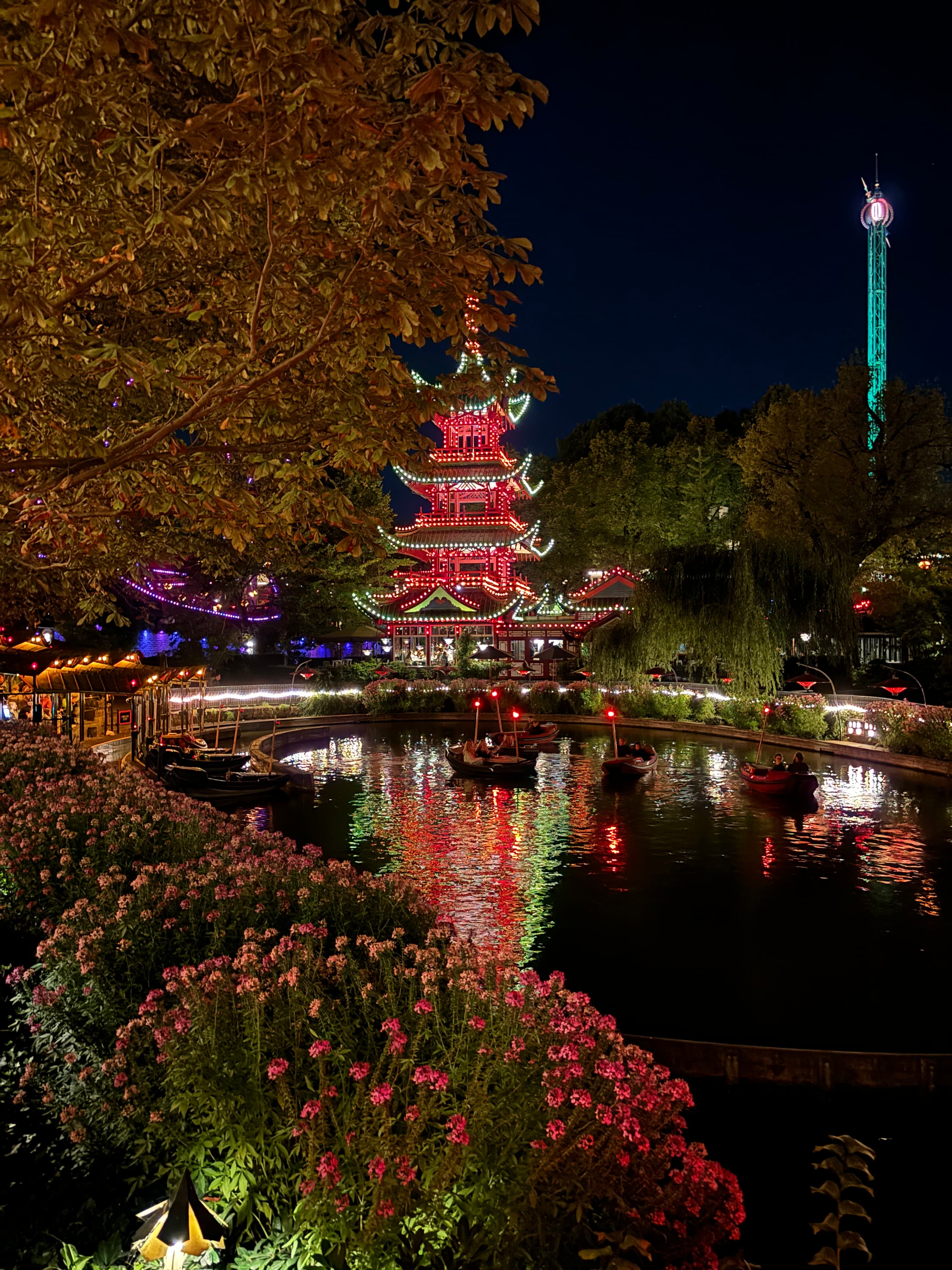A body of water in front of a temple, lit up at nighttime