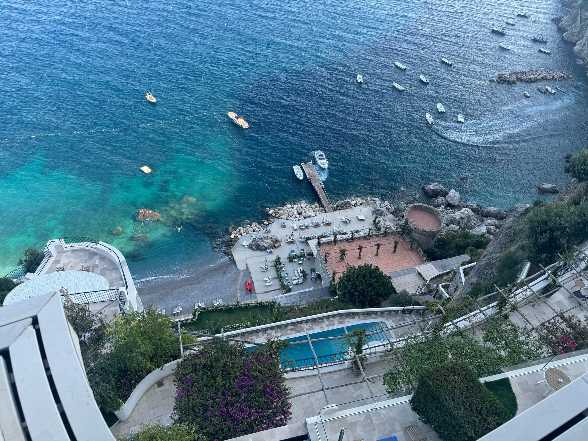 Bird’s eye view of a small beach and boats floating off a small dock