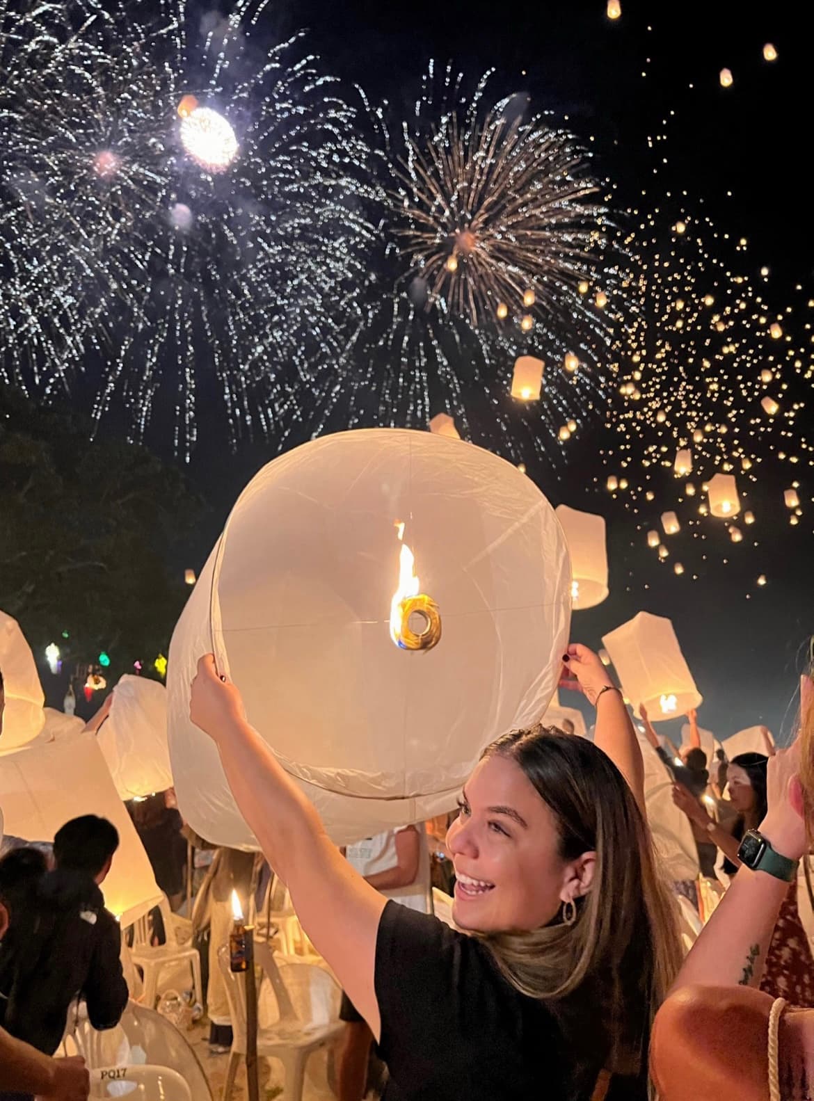 Advisor holding a large white paper lantern with fireworks overhead
