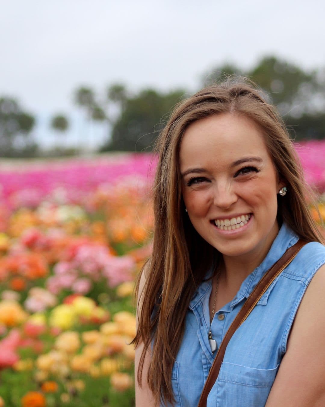 Advisor smiling with a field of colorful flowers in full bloom behind her
