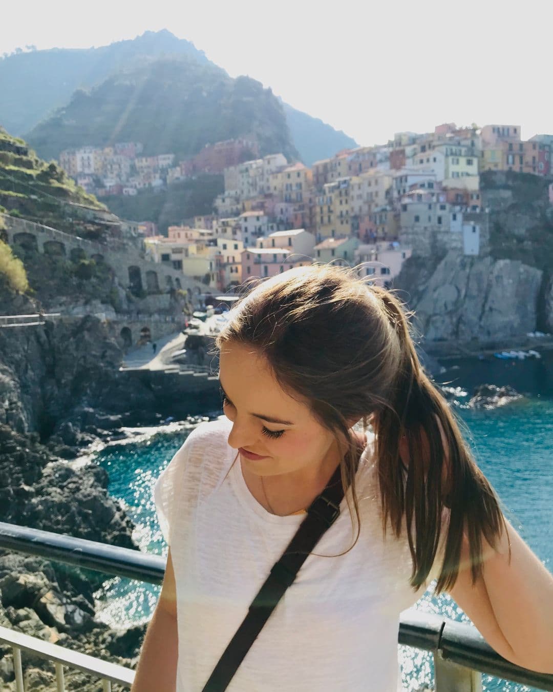 Advisor with head turned away from the camera and a coastal town in Italy on the cliffside behind her