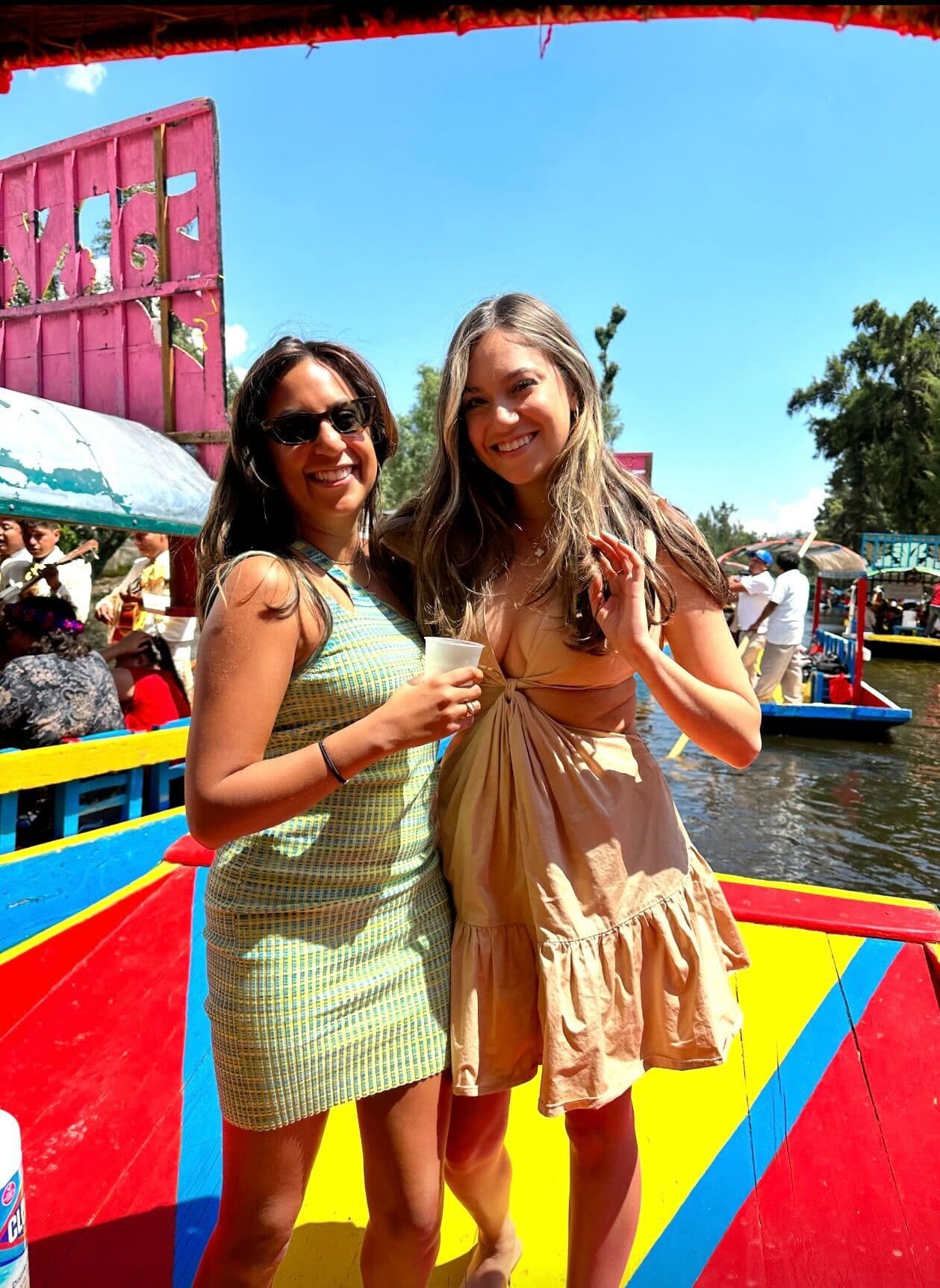 Alexa and friend posing on a colorful boat during the daytime.
