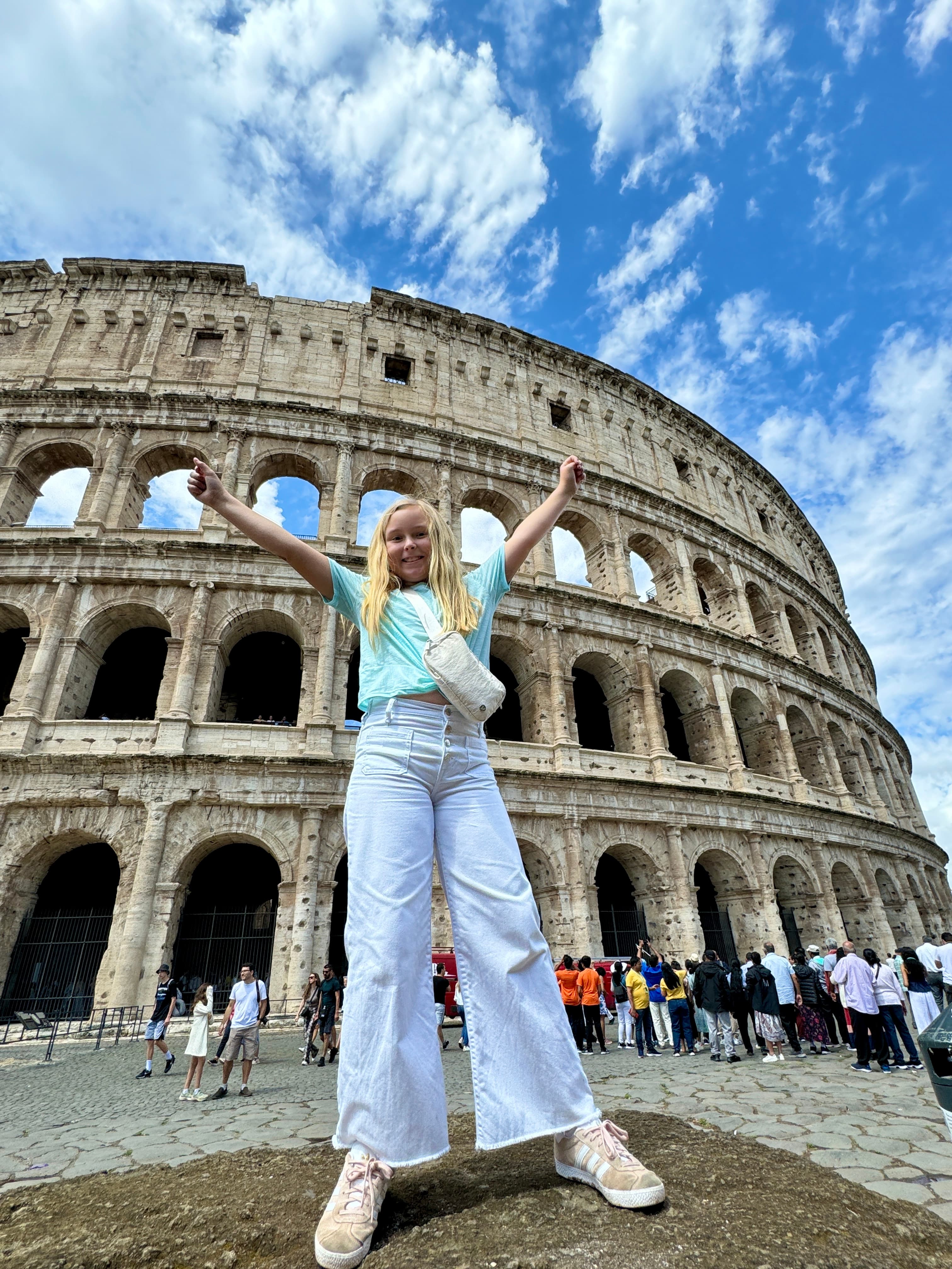 Advisor standing with arms raised in front of the Colosseum on a sunny day in Rome