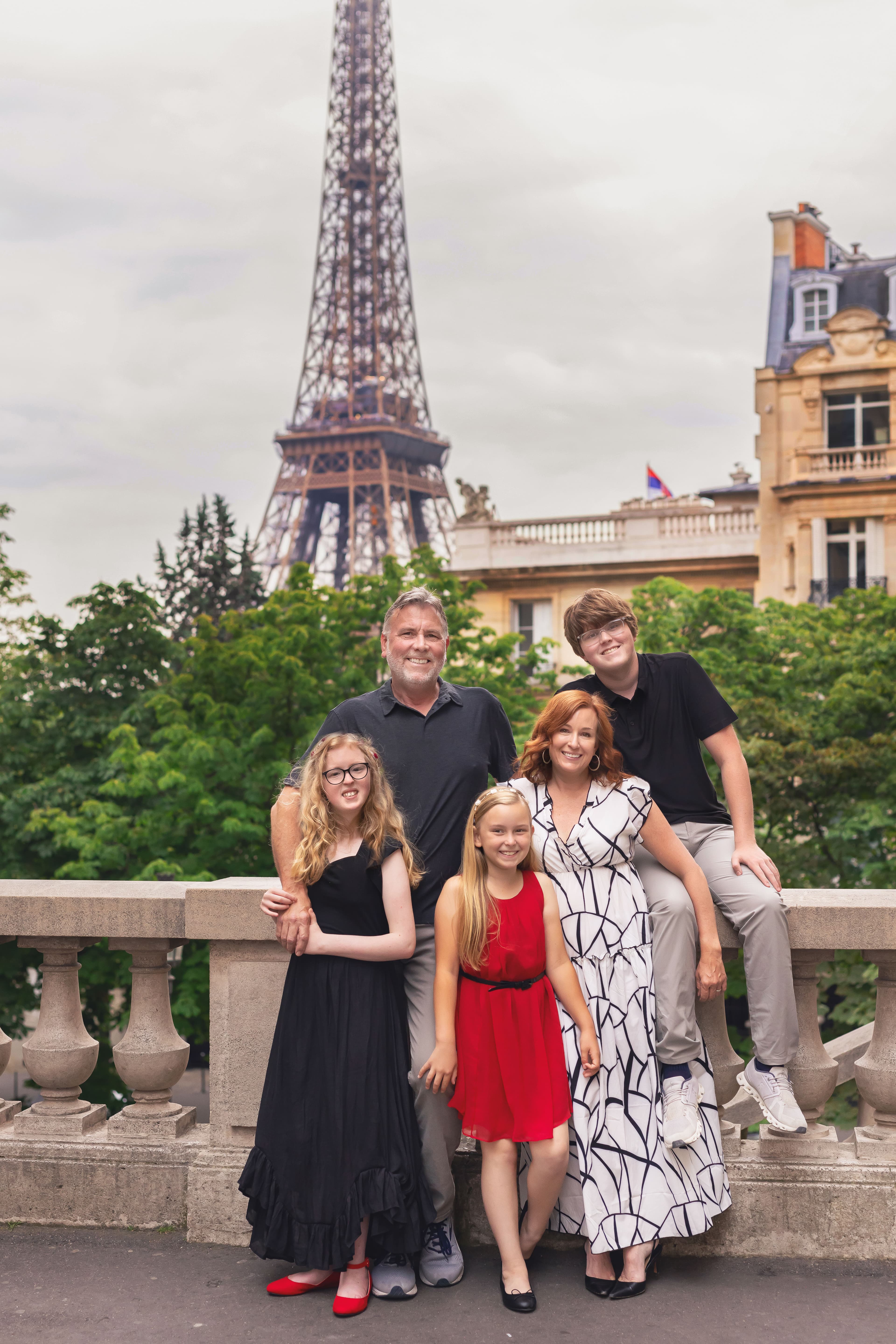 Family posing with the the Eiffel Tower in the distance.