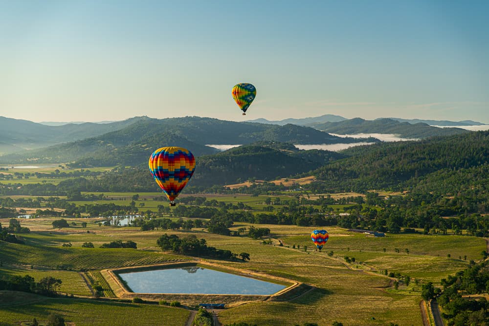 View of two colorful hot air balloons mid-flight over Napa Valley