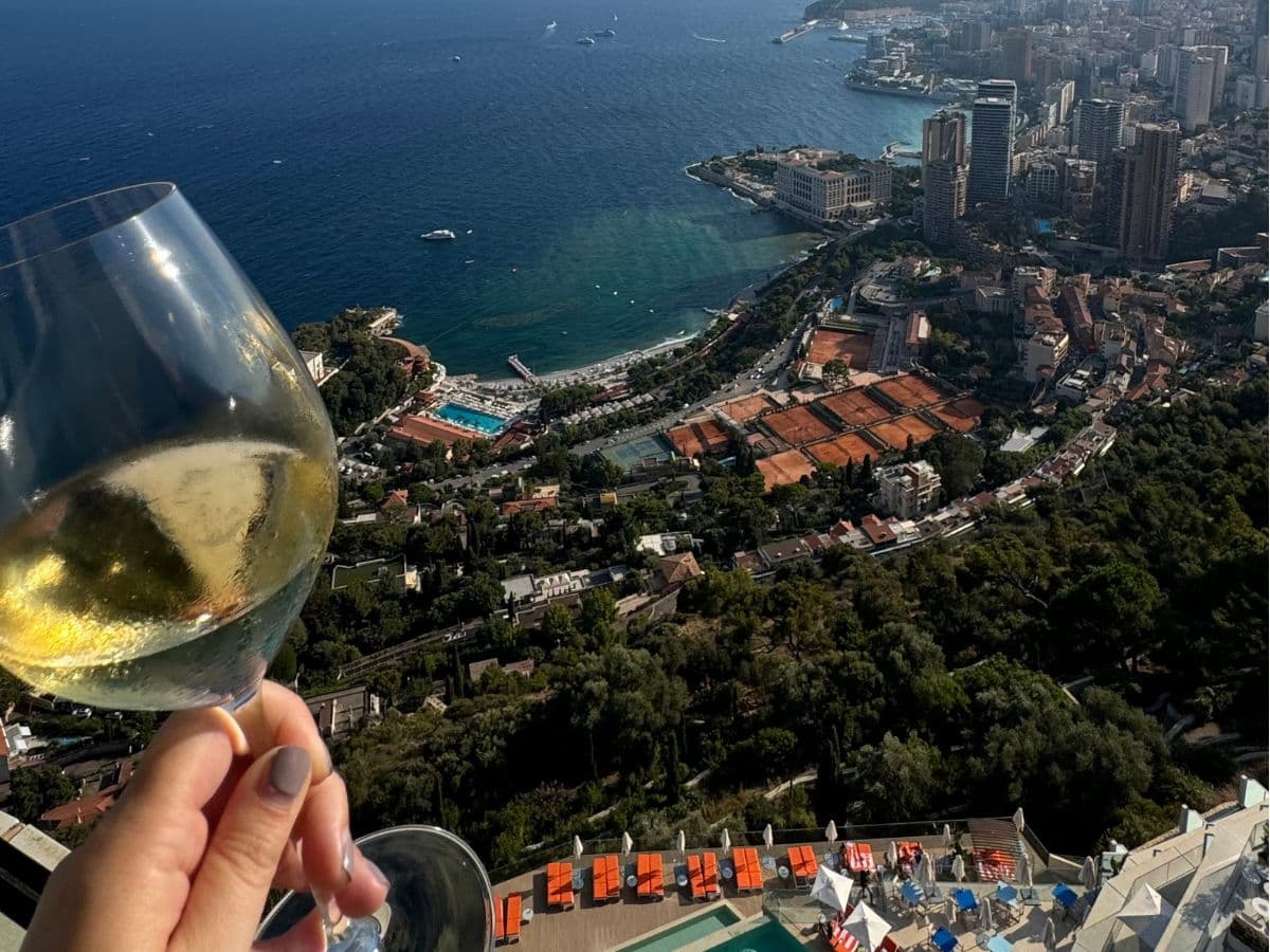 A view of a seaside town with a city in the distance and a shoreline on a sunny day.