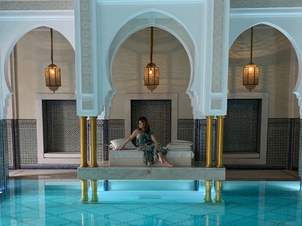 Advisor posing on a luxurious couch with a pool and upscale interiors.