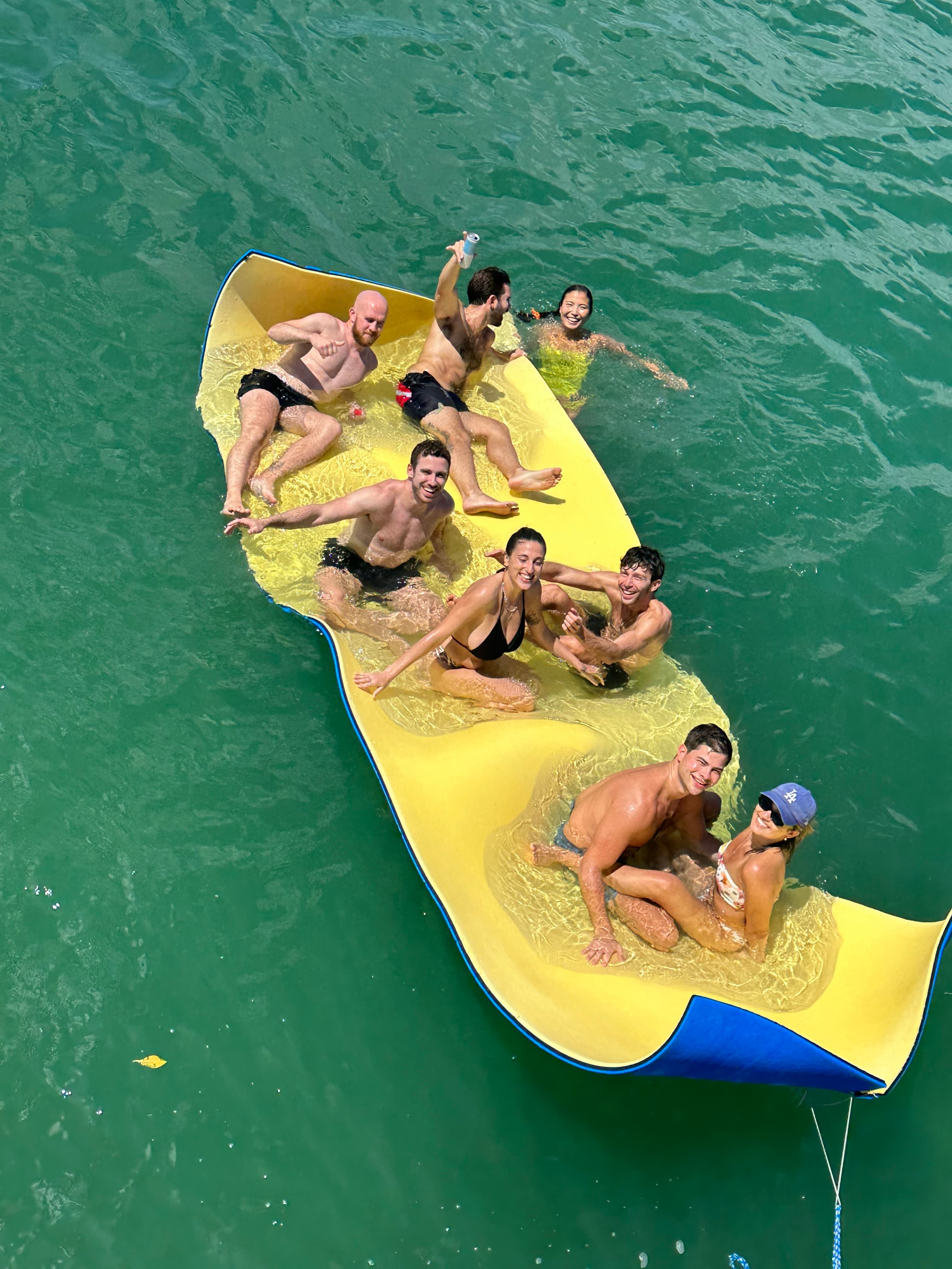 Overhead view of a group of people sitting on a yellow raft at sea