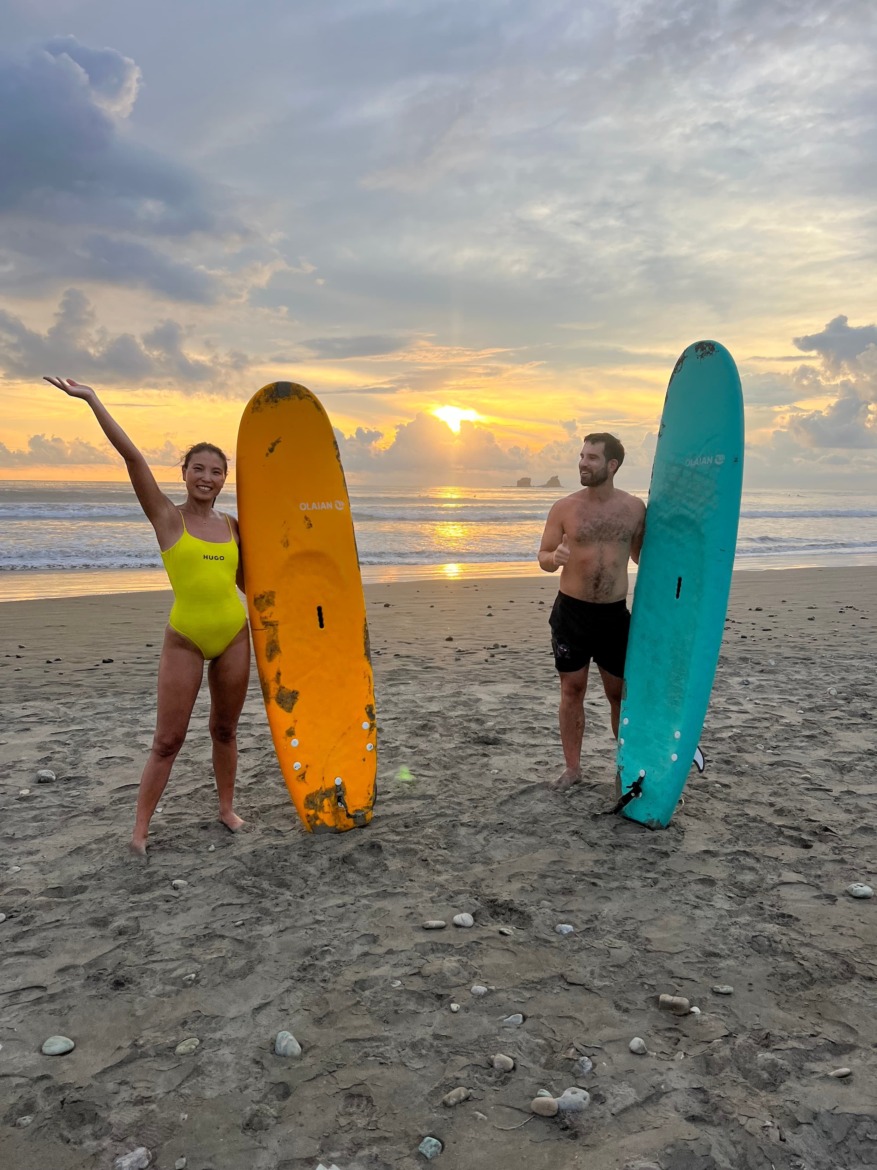 Advisor and a man standing on the beach at sunset with paddle boards in hand