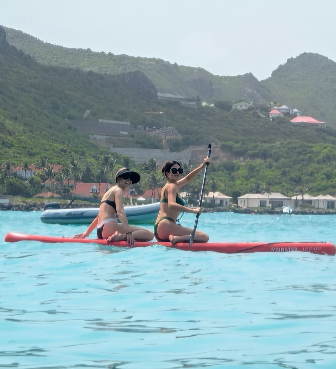 A image of the advisor paddle boarding in the ocean with a mountain scape in the distance.