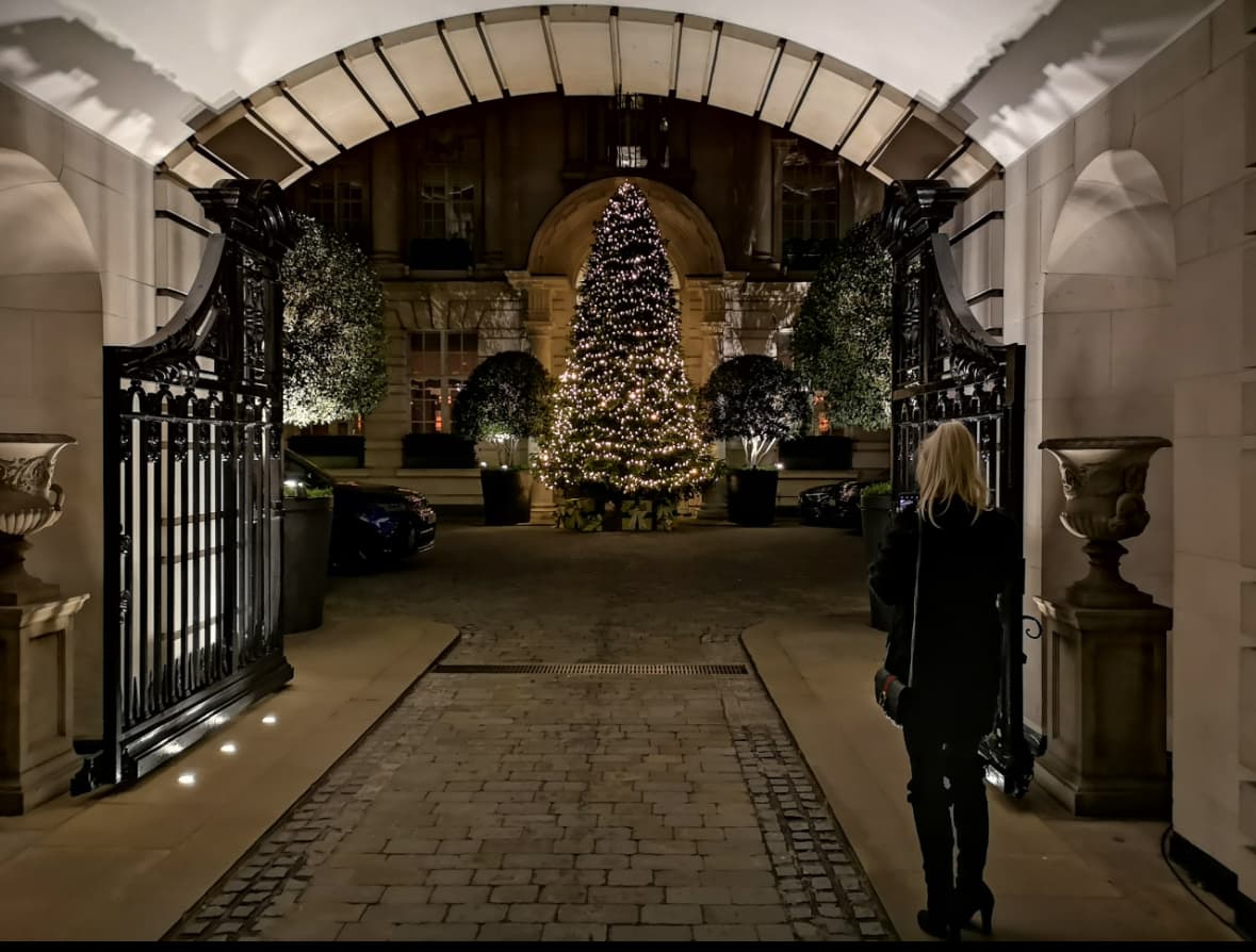 A view of a Christmas tree at night surrounded by lights.