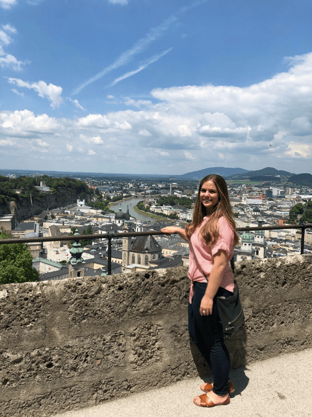 Advisor posing at a lookout point over a city with a river running through it