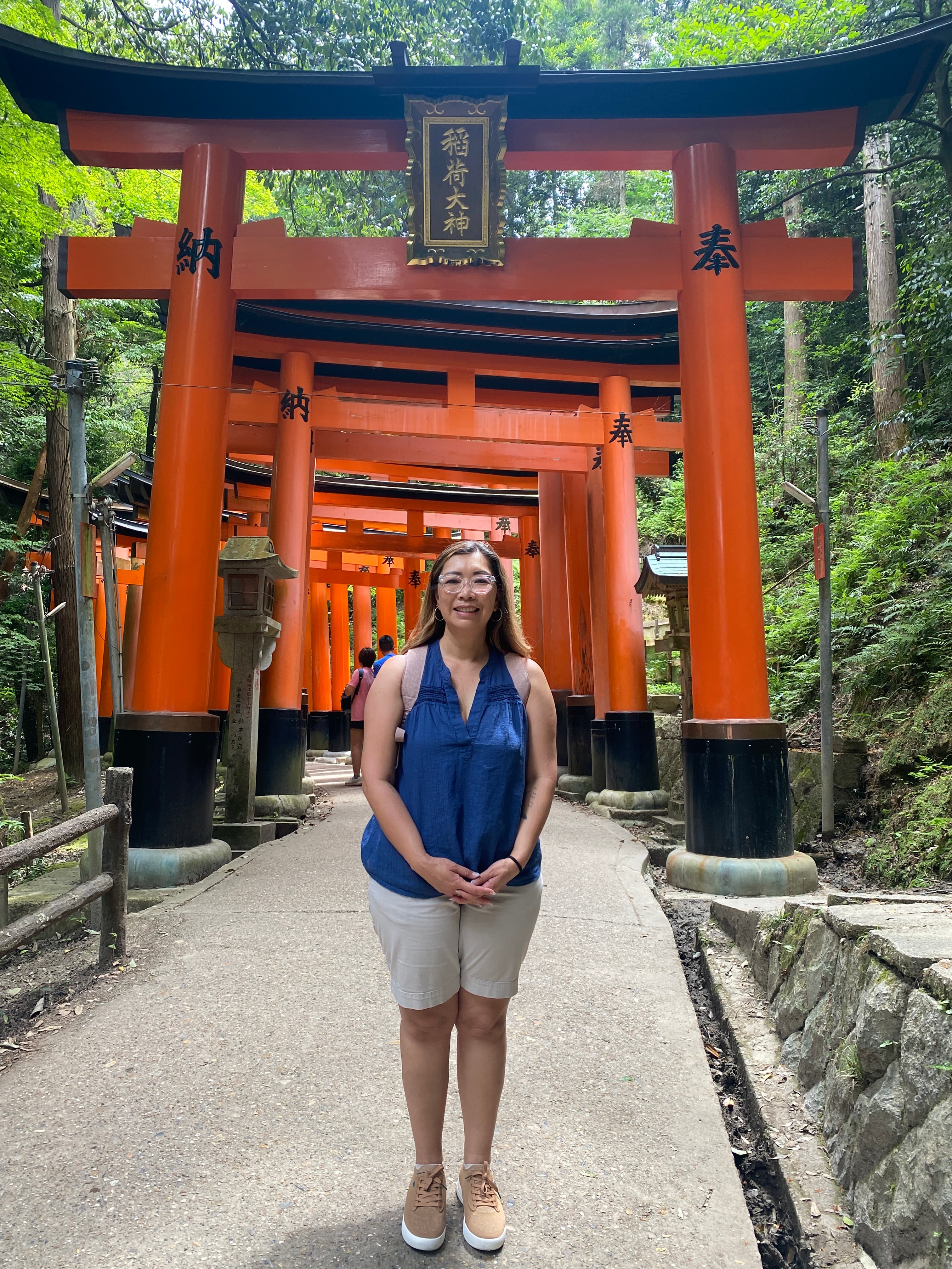 Advisor posing on the pathway beneath a Japanese Torii gate lined with trees