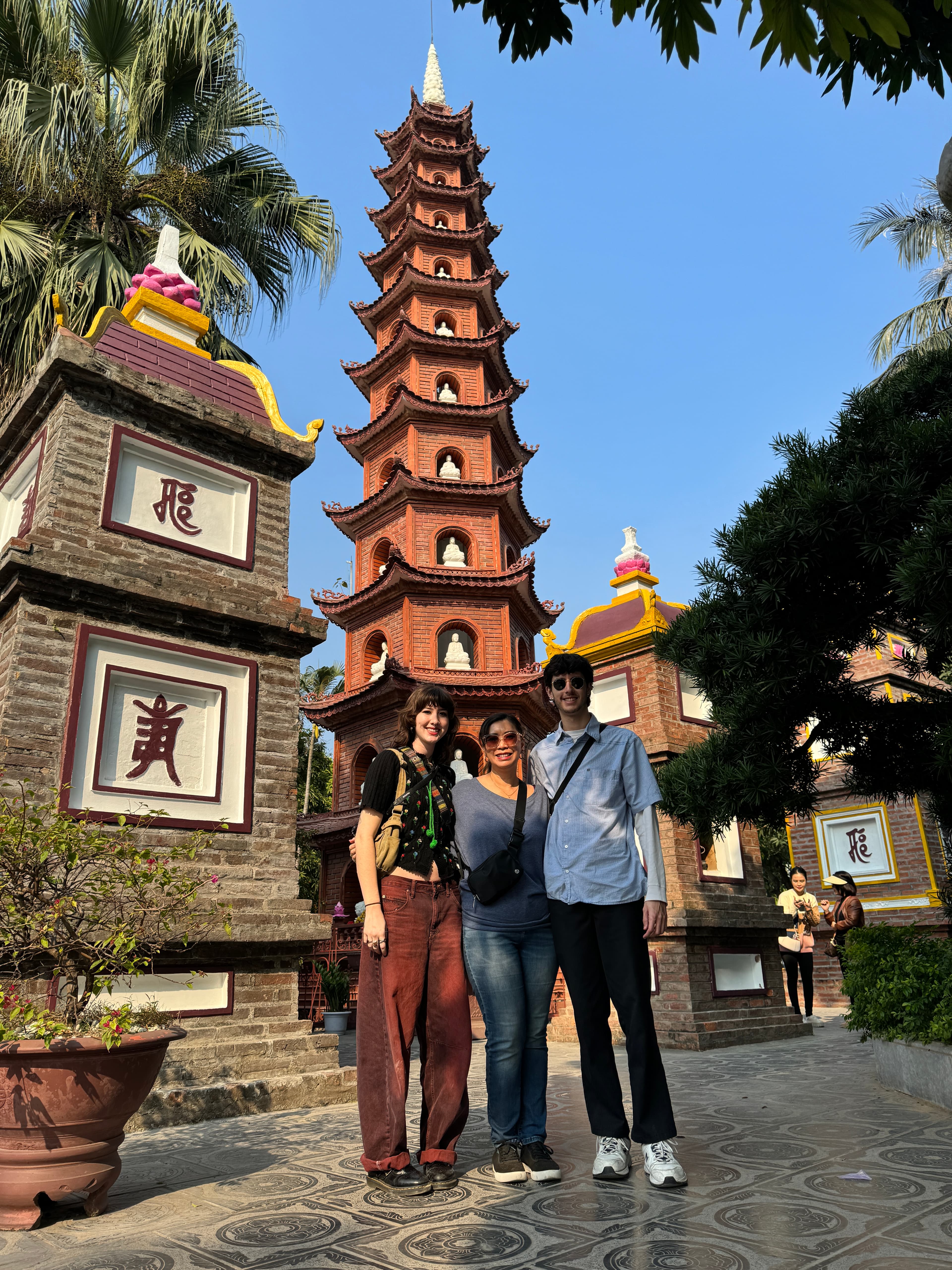 Advisor and family side by side in front of a tall temple structure on a sunny day