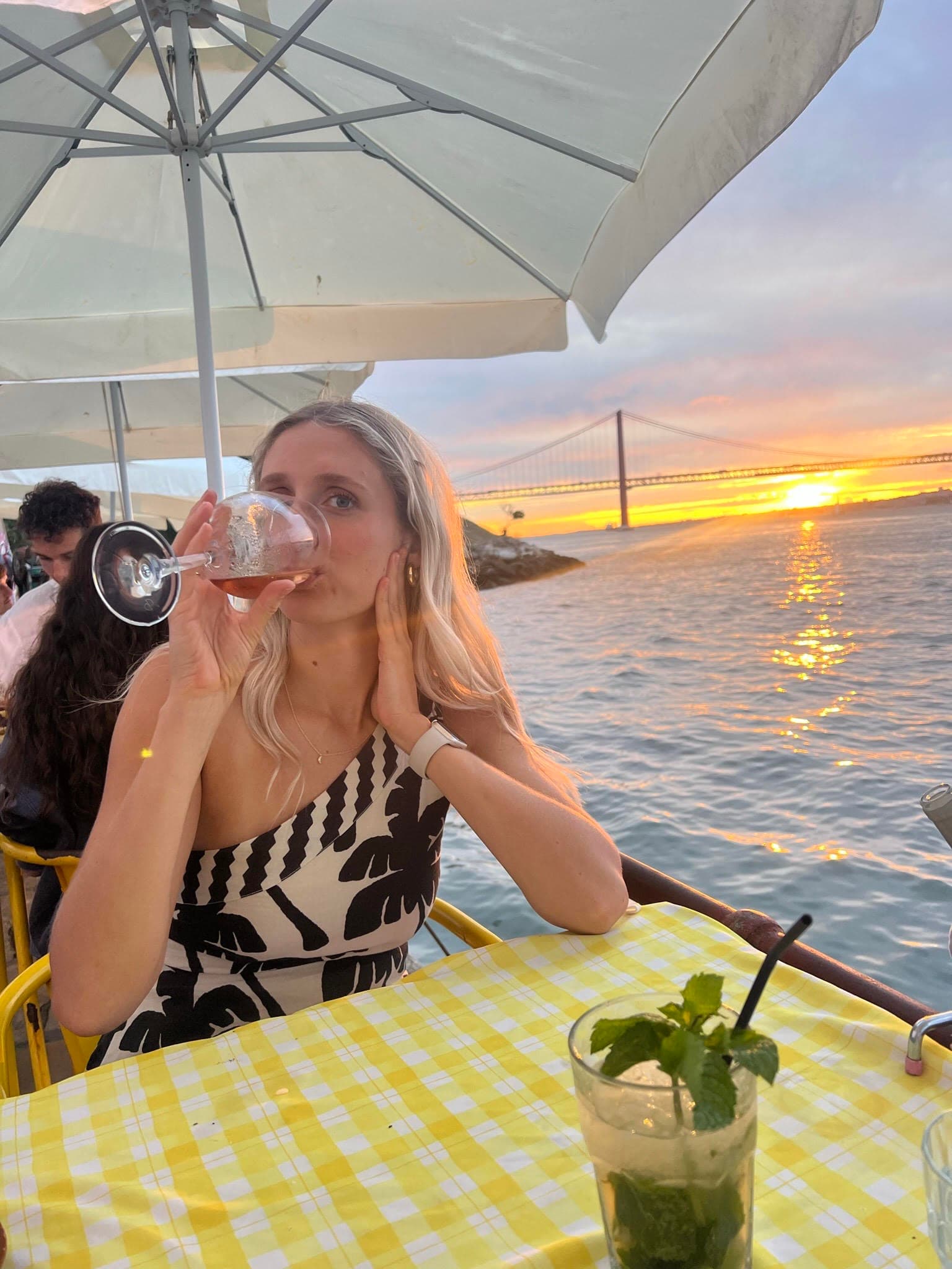 Advisor sitting at a table next to a body of water drinking from a glass of wine