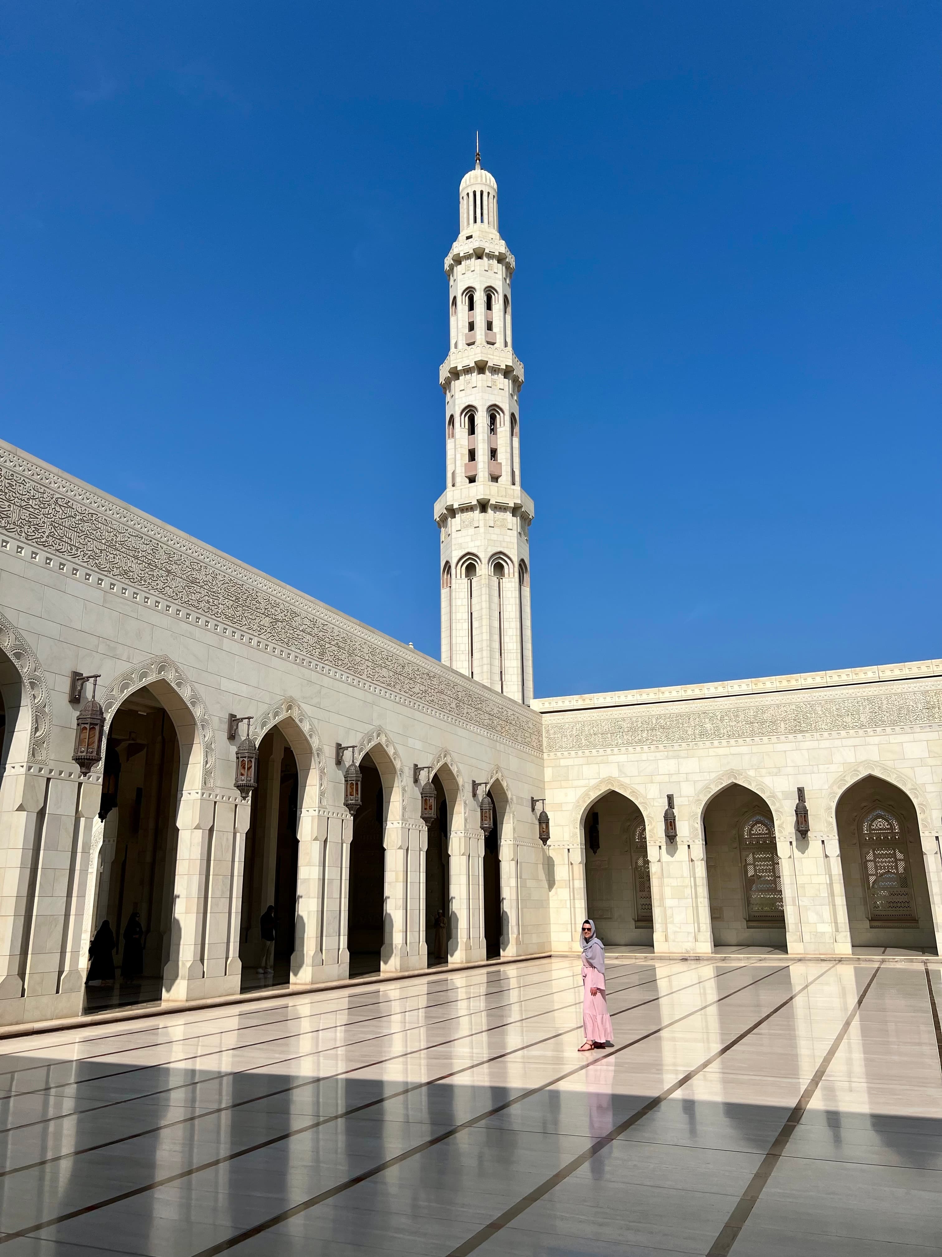 View of a marble courtyard with white tower rising above on a clear day