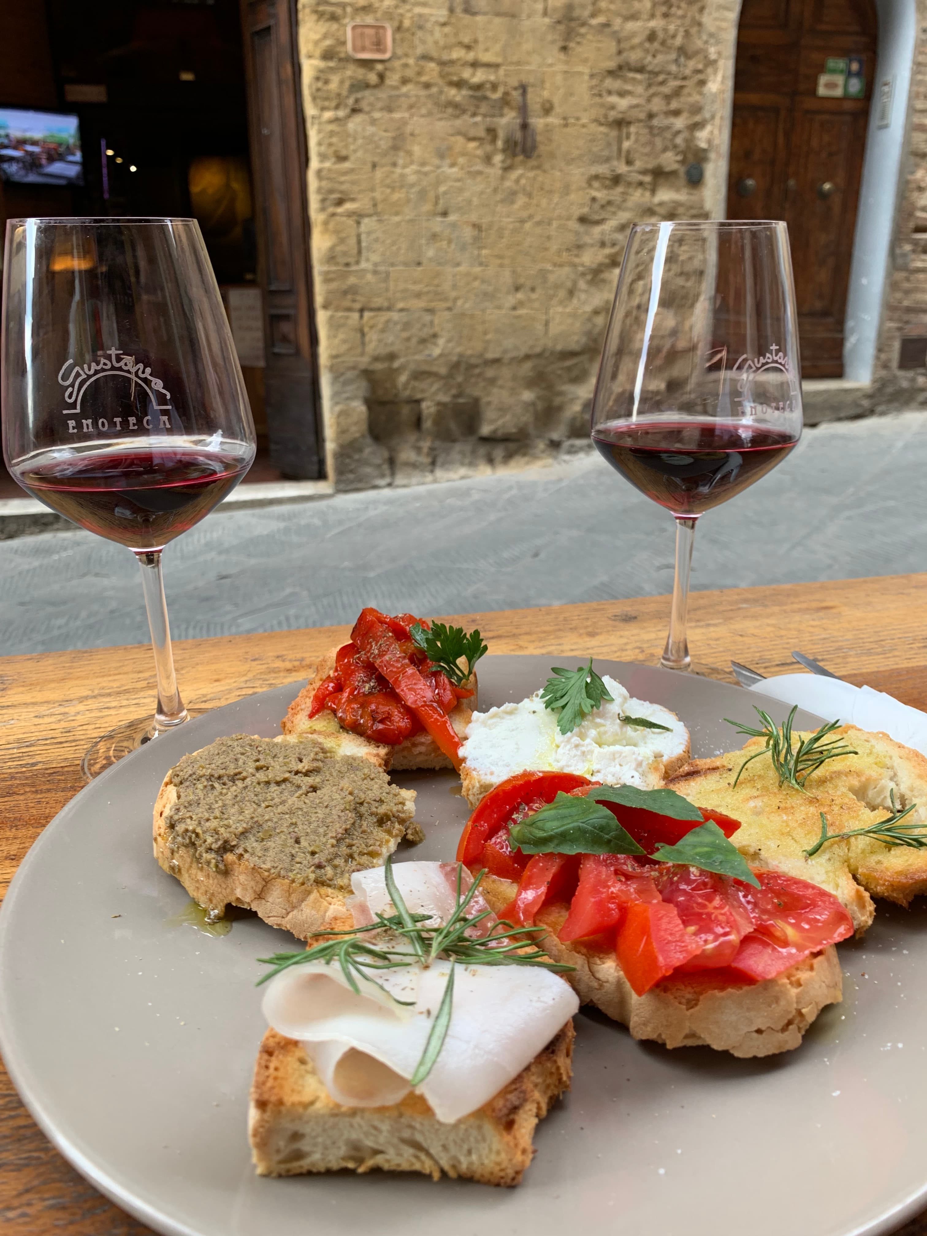View of a plate of bruschetta and two glasses of red wine on the sidewalk