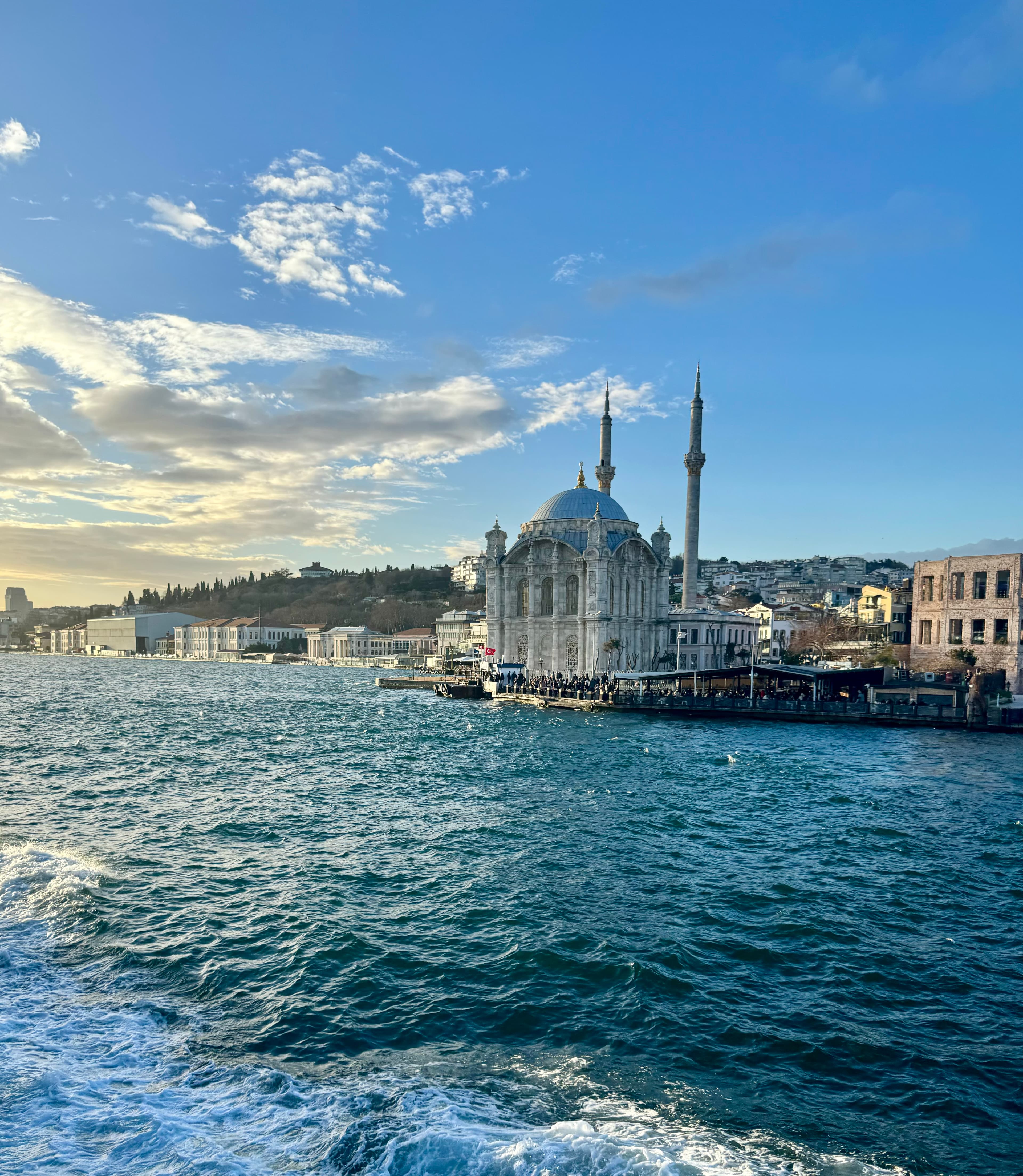 View of a large mosque in Istanbul with two minarets seen from across the water on a clear day