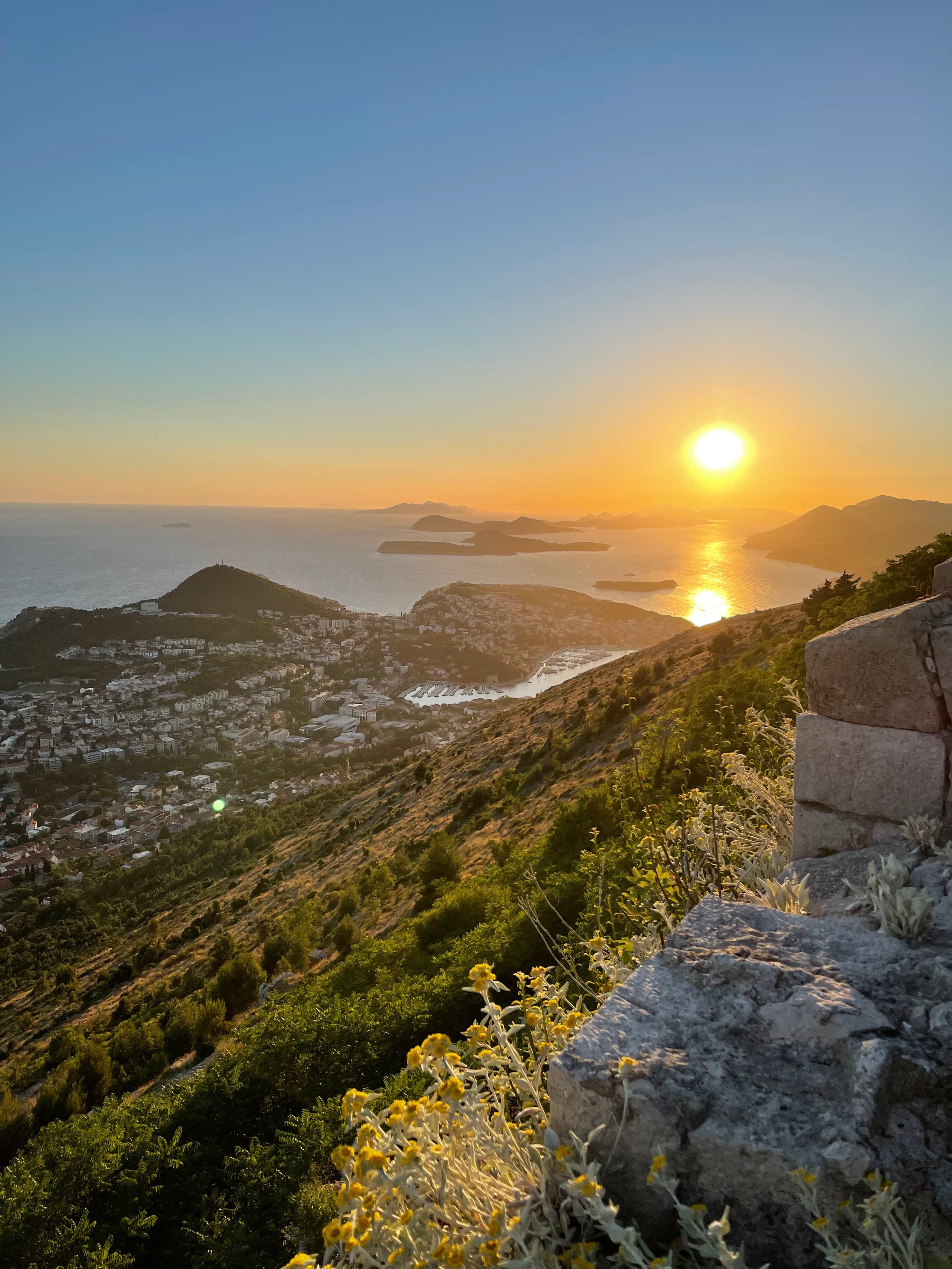 View of the sunset over a coastal town as seen from a hilltop