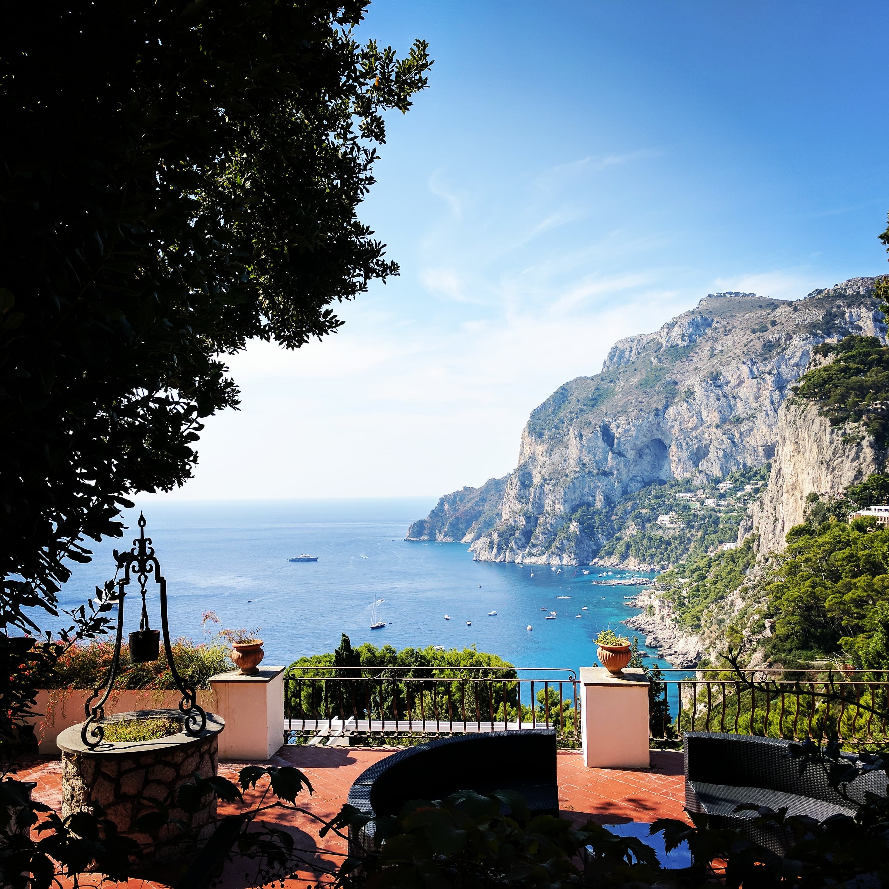 A view of a coastal town on the ocean with a mountain in the distance during the day.