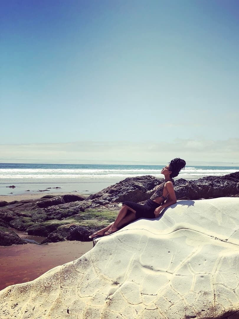 Advisor leaning back and resting on the sand while looking out over the sea on a clear day