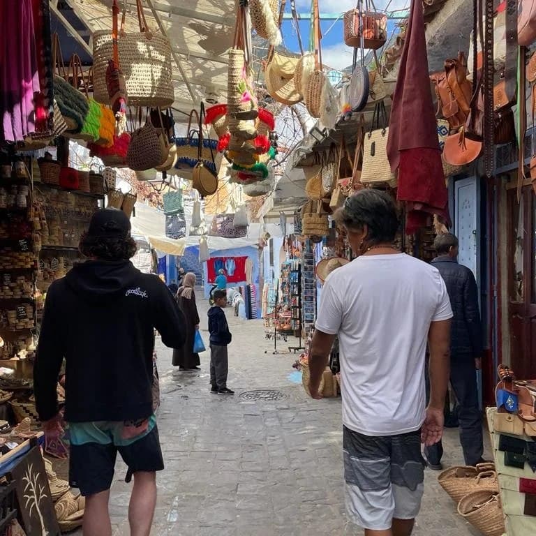 View of two people walking down the street of an open-air market during the day