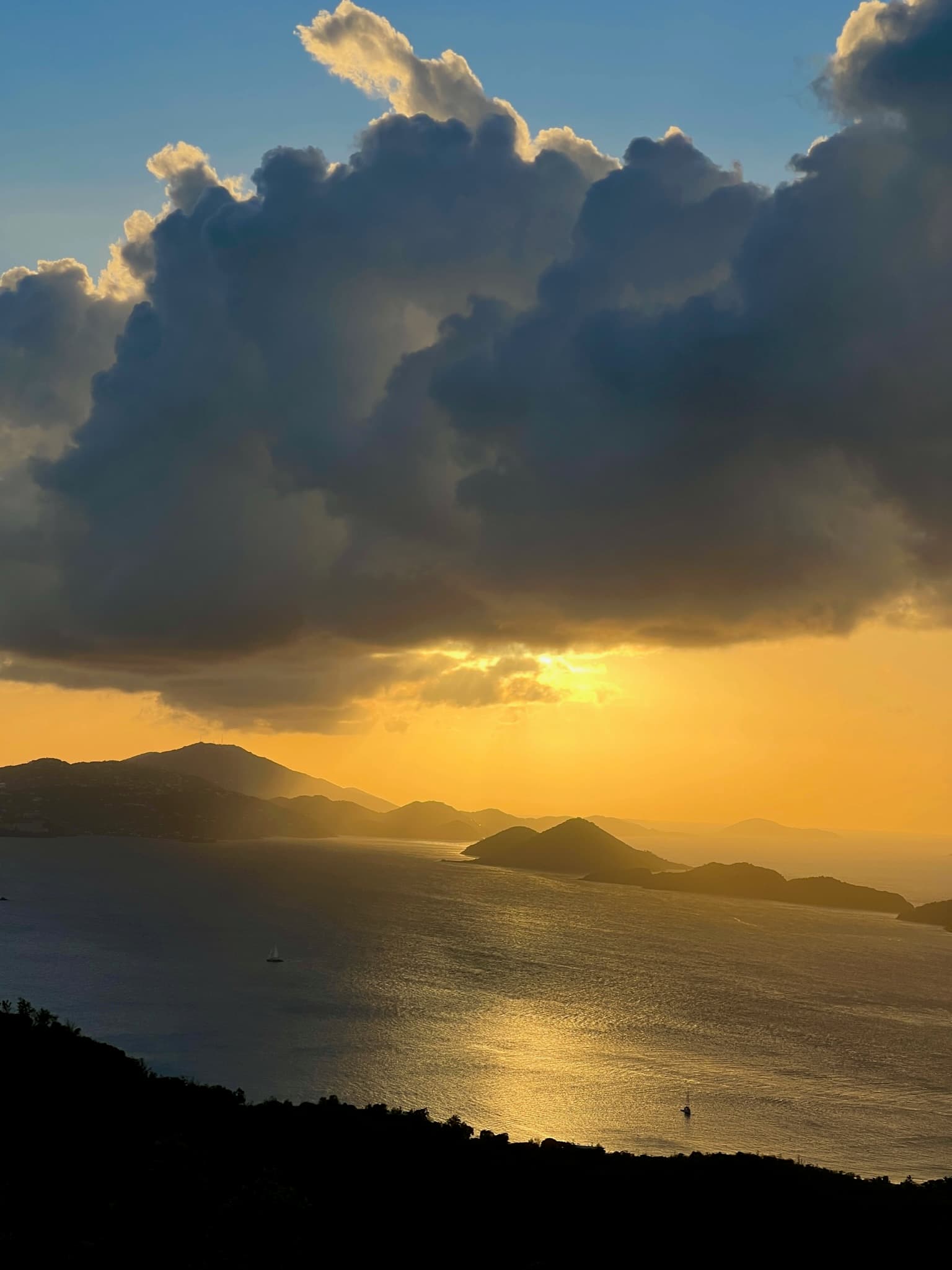 View of sunset over the sea emerging from below a large cloud