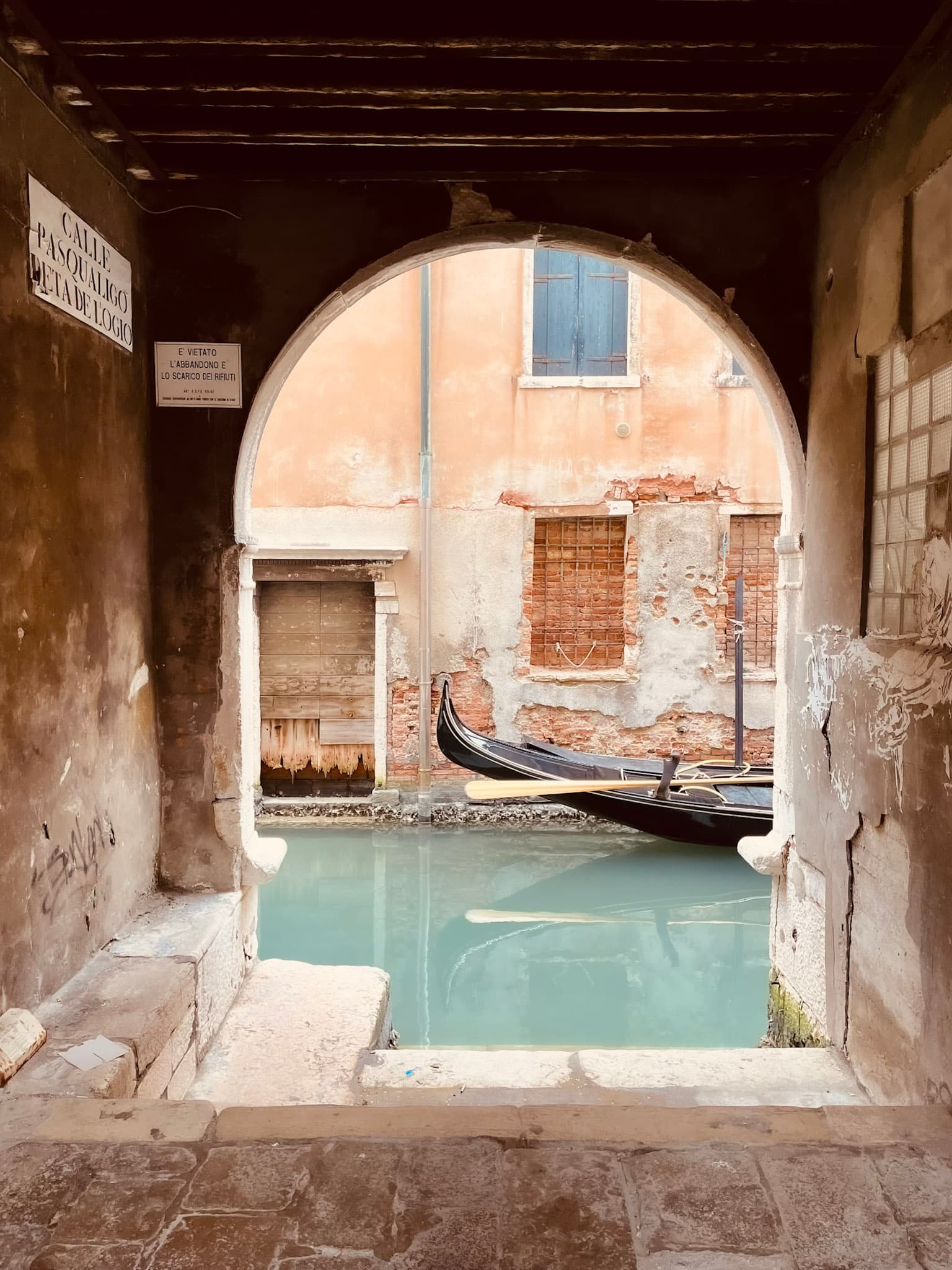 Partial view of a gondola on a canal in Venice as seen through an arched opening