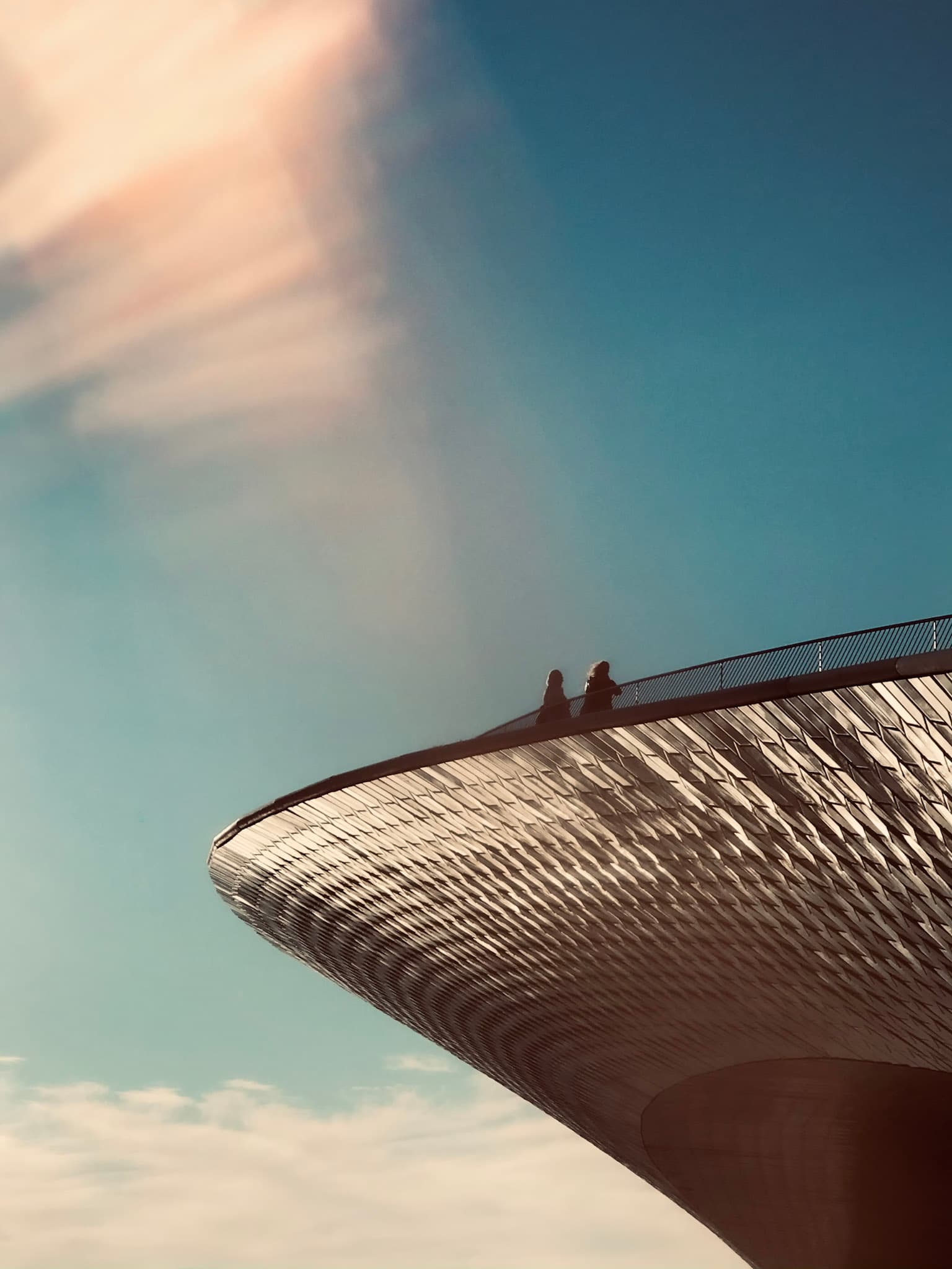 Faraway view of two people standing in silhouette on the edge of a tall building
