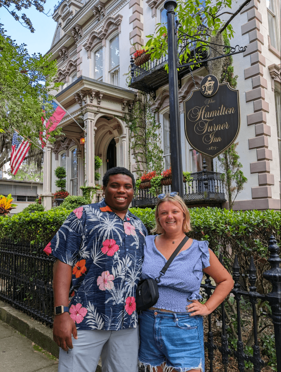 Advisor and a man in a floral-print shirt smiling together in front of beautiful hotel