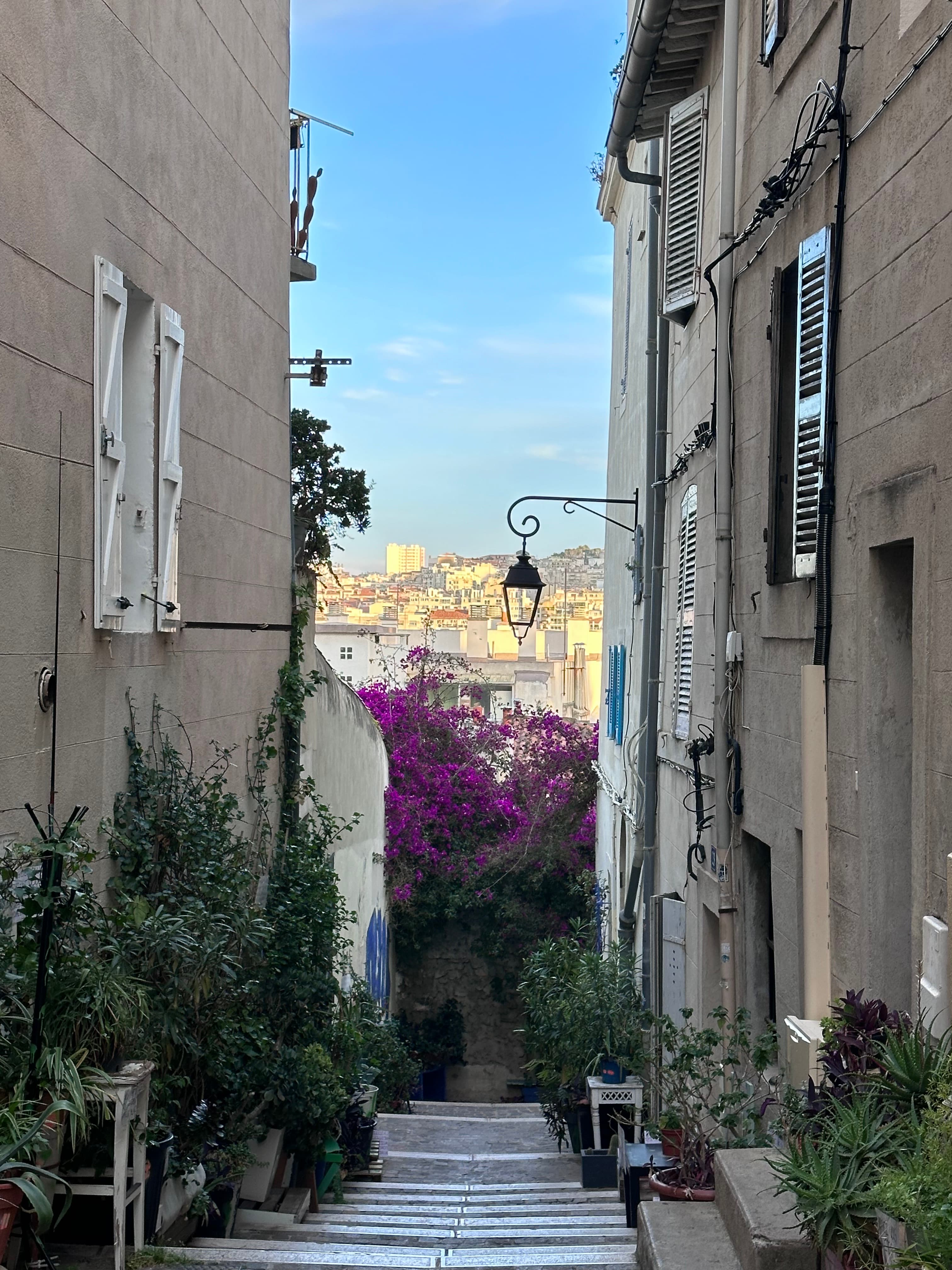 View of a narrow road between residential buildings with a sunny town visible in the distance