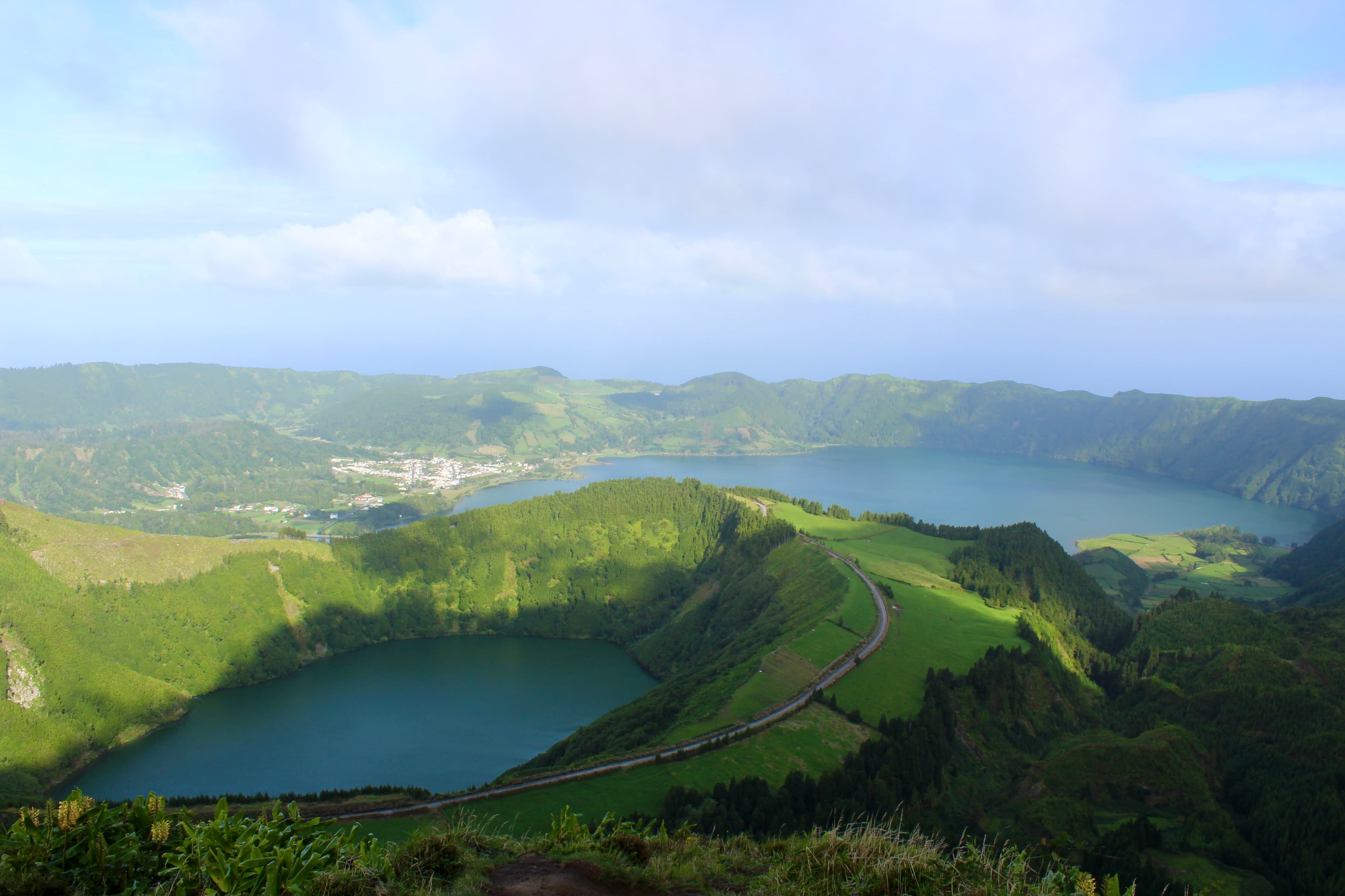 Aerial view of a beautiful lake and surrounding green mountains on a sunny day